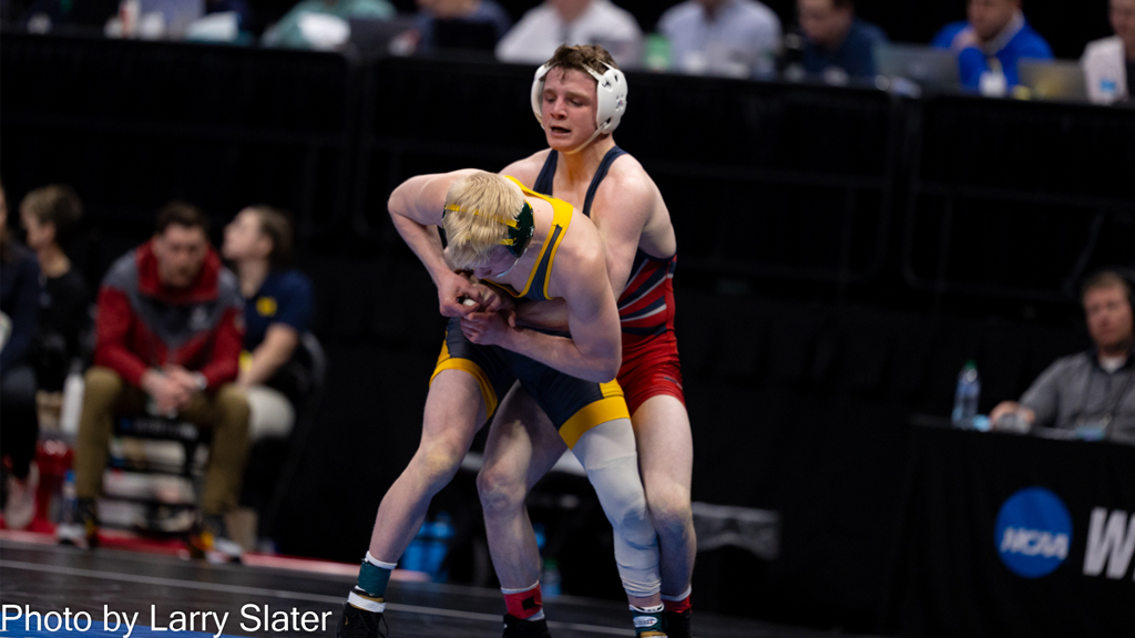 Composto grabs a wrestler around the waist during a match.