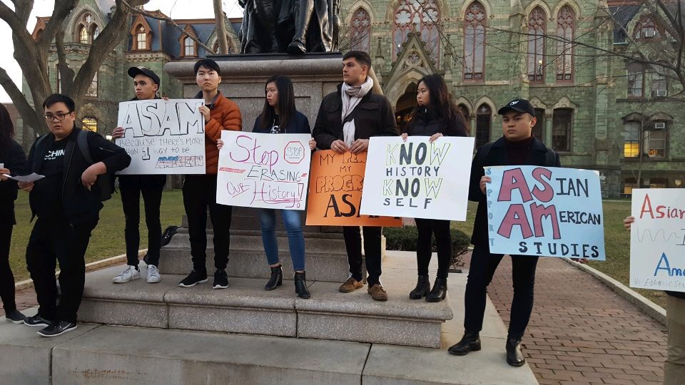 A group of students stand in front of College Hall with signs in support of ASAM