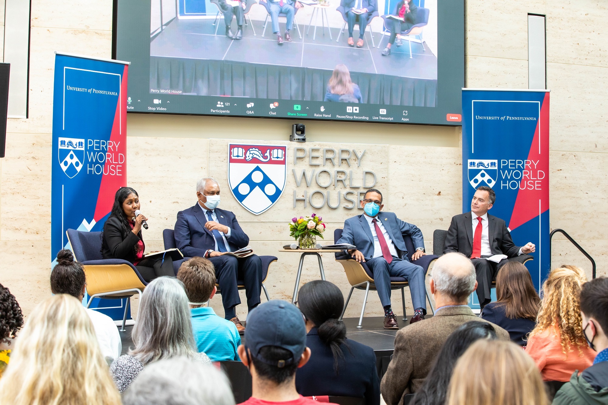 Four people sit on a stage at Perry World House.