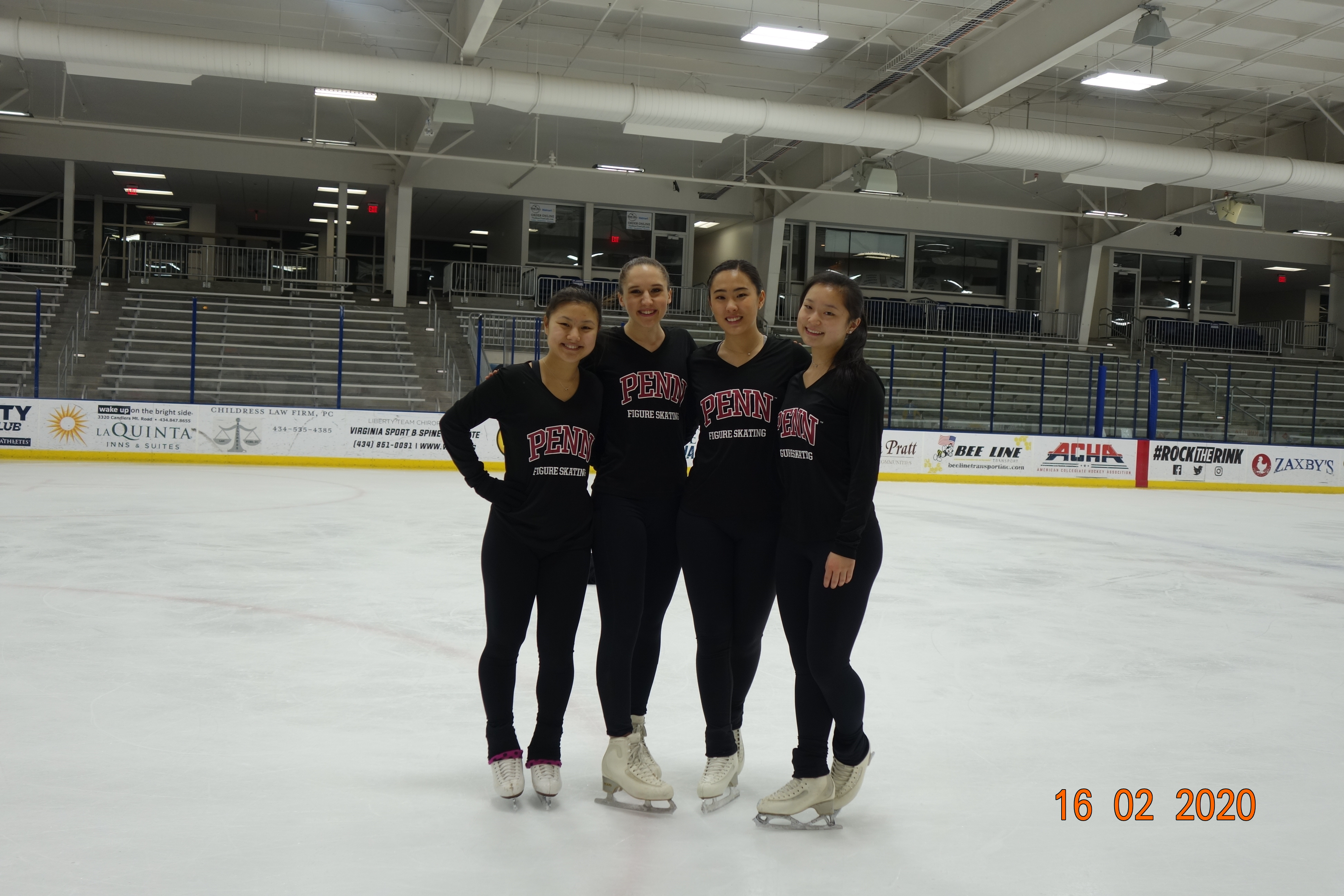 Four women stand on an ice rink with sweatshirts that say "Penn"