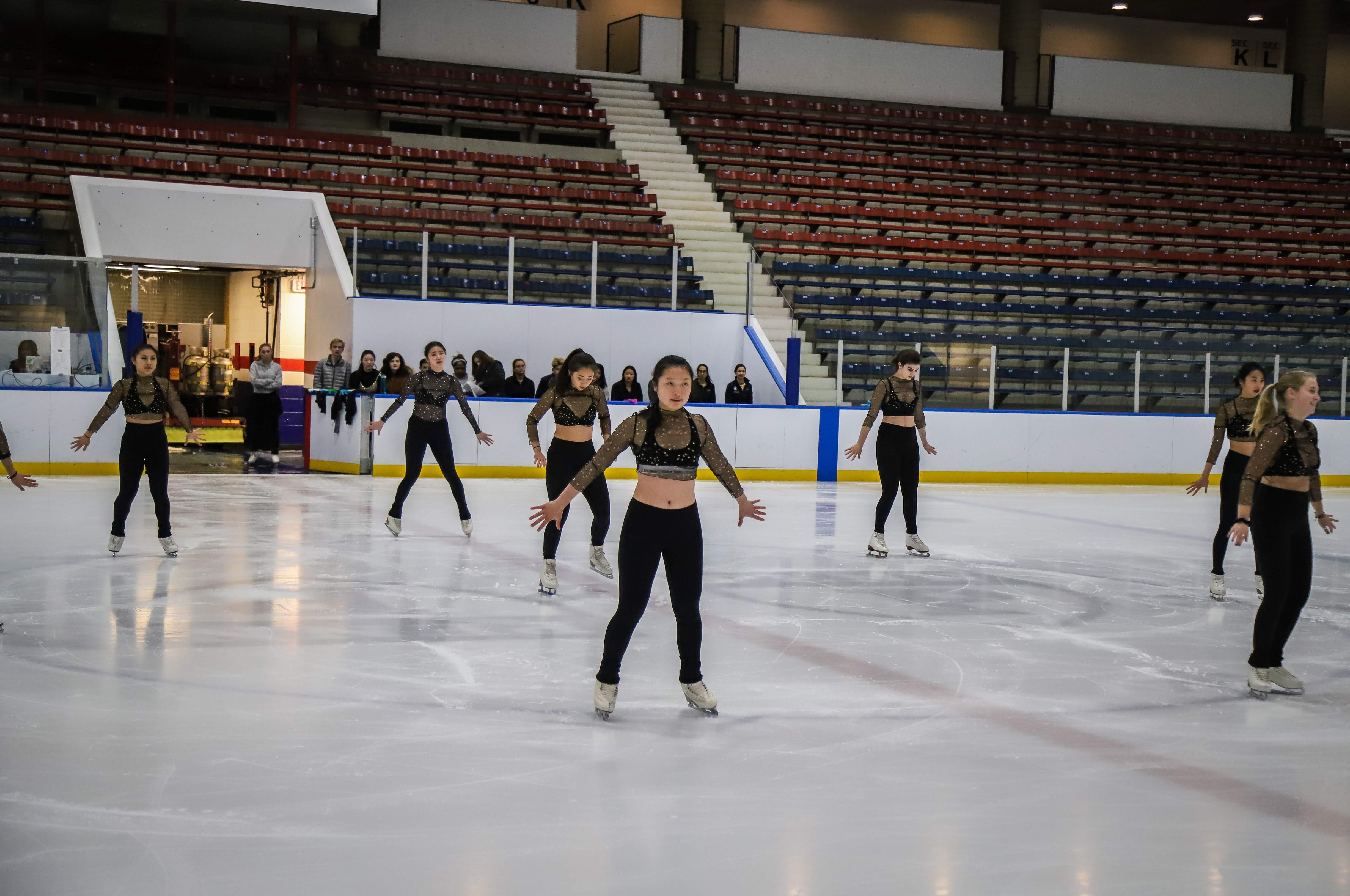 A team of ice skaters wearing sparkly costumes in formation