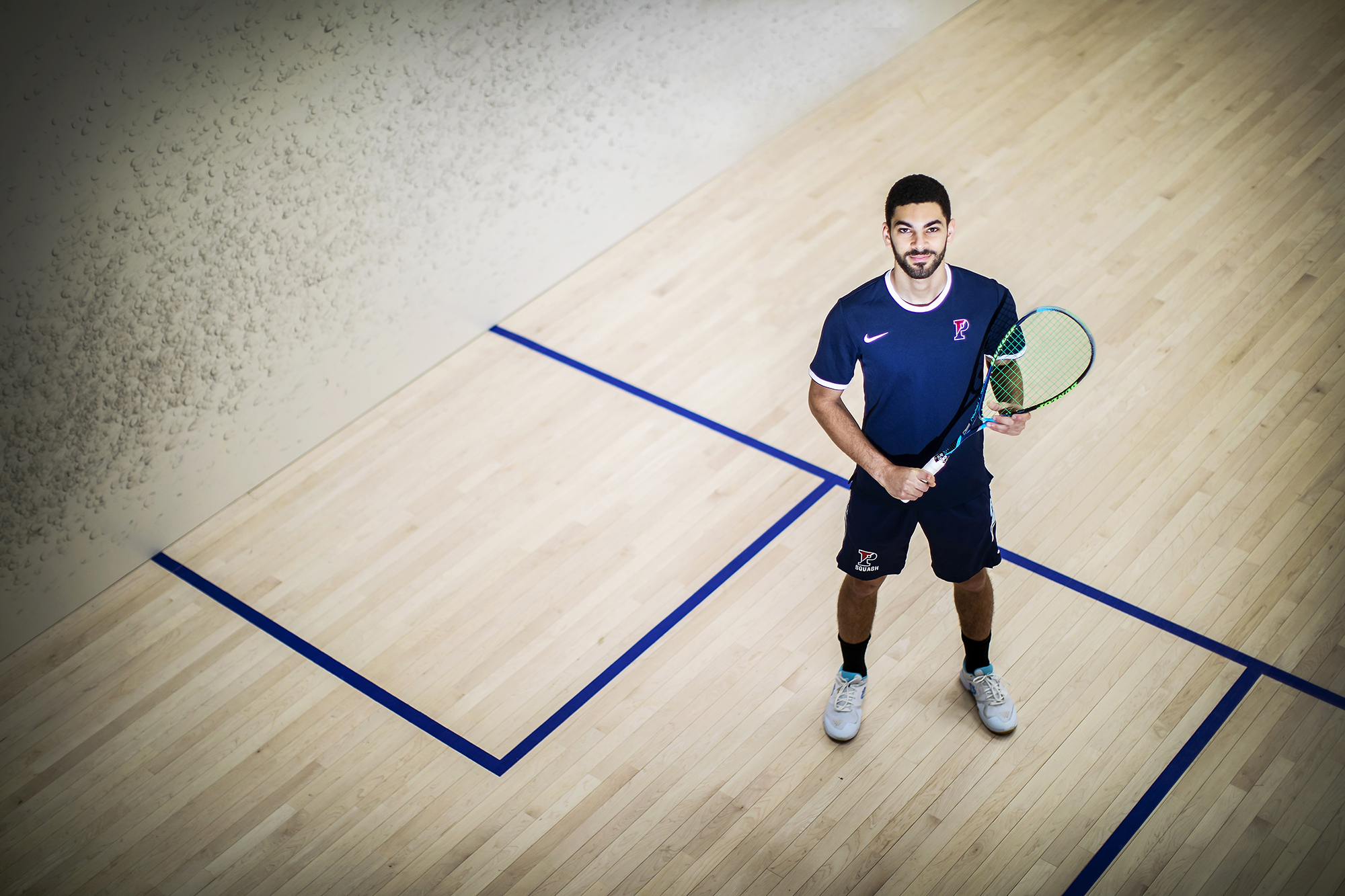 Aly Abou Eleinen holds a racquet inside the Penn Squash Center.