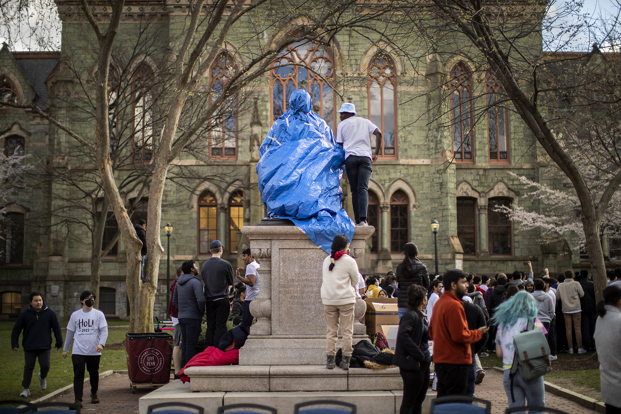 Students cover the statue of Ben Franklin in front of College Hall with a tarp.