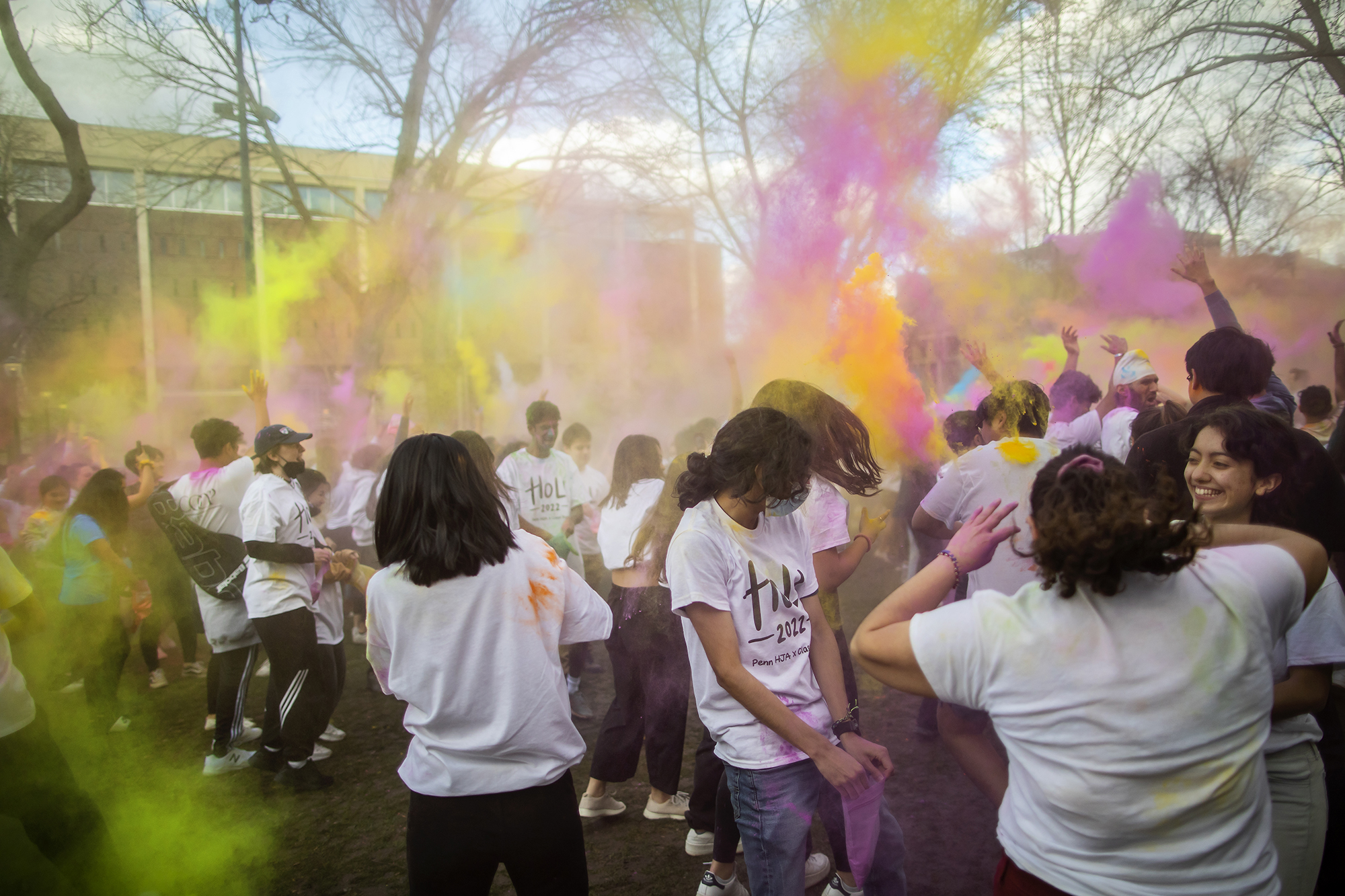 Students throw colorful powder into the air on College Green.