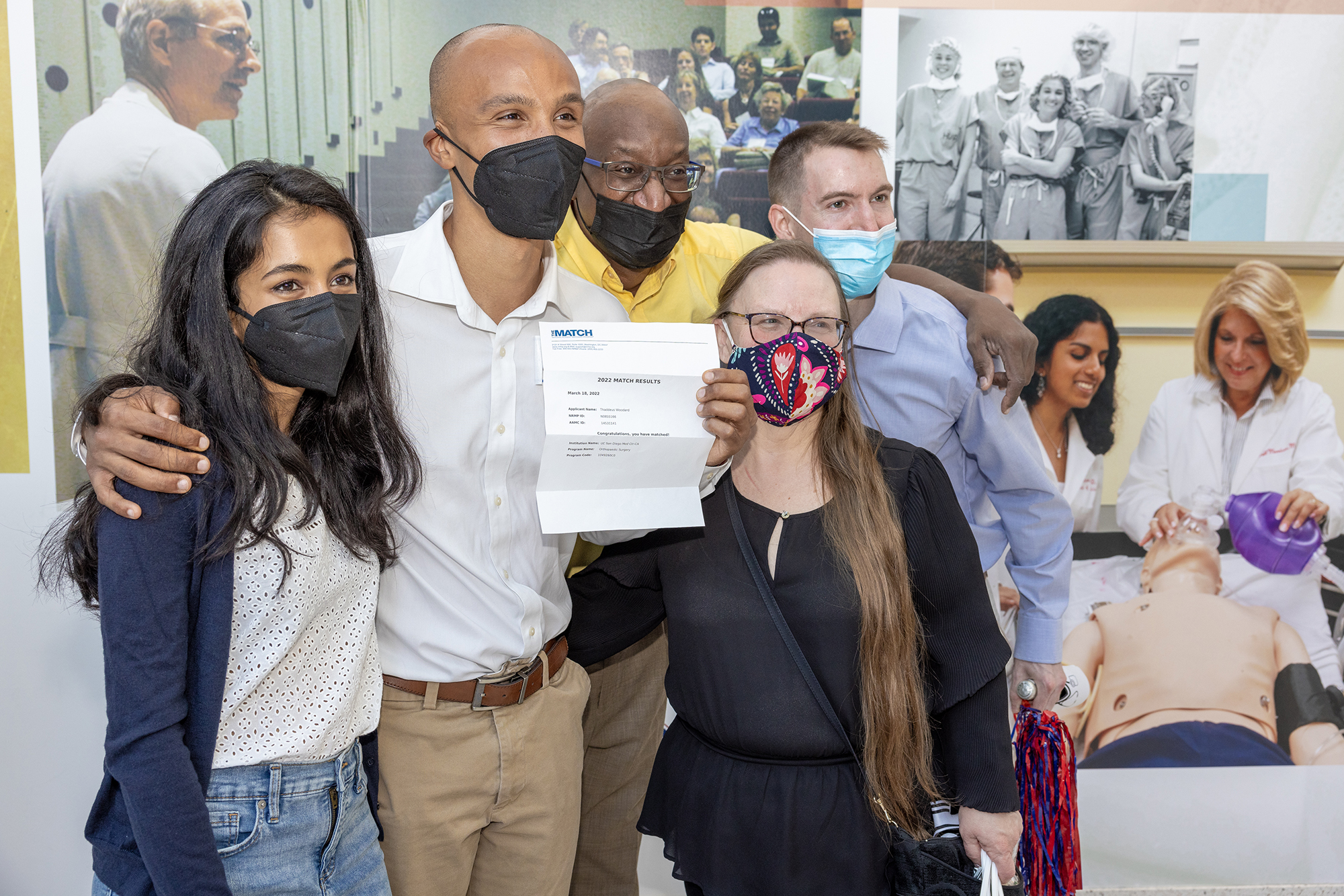 Penn Med student Theo Woodard smiles while holding up their Match Day letter.