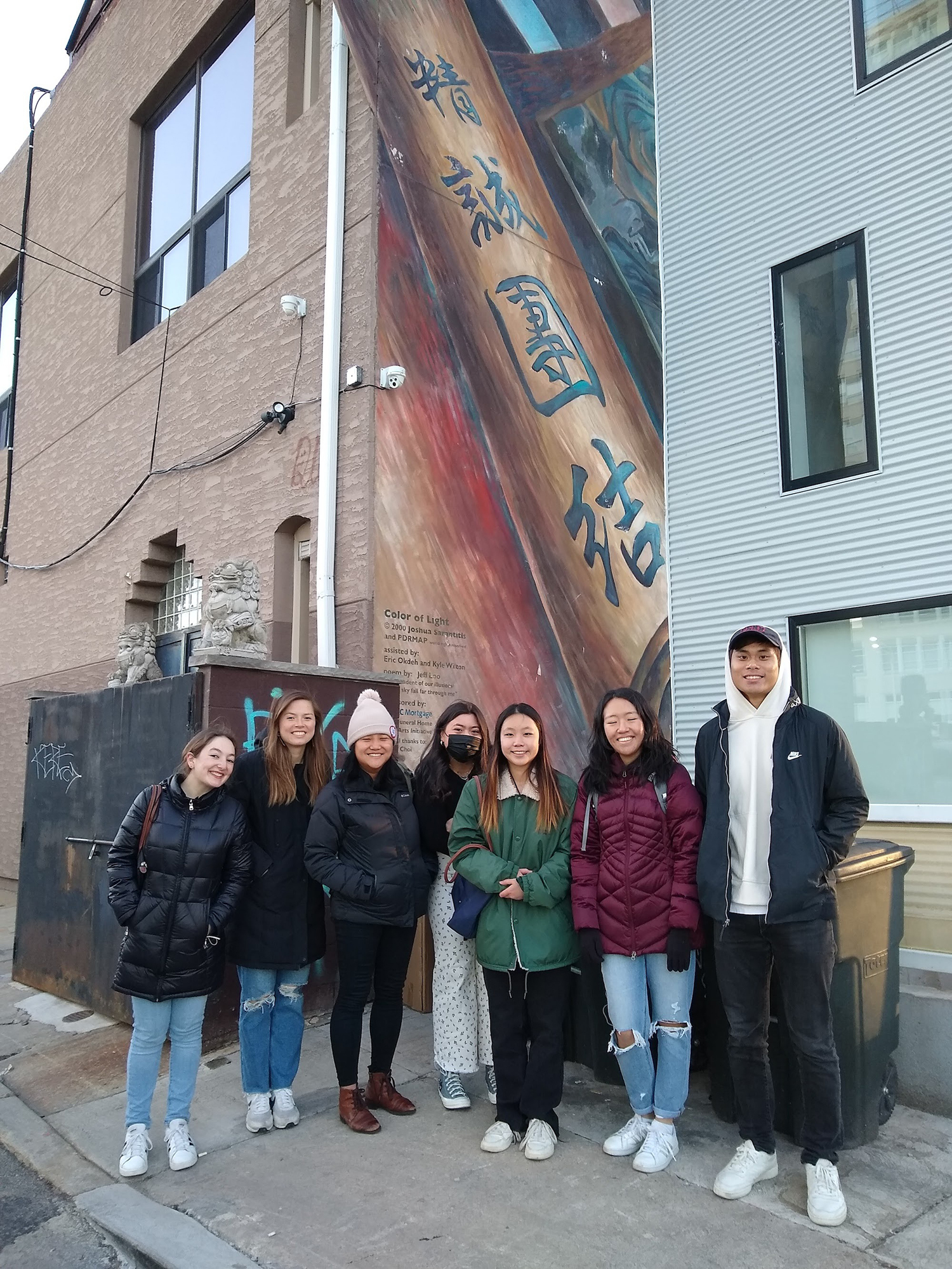 Students in Sarah Yu's Chinese diaspora's class stand in front of a mural in Chinatown