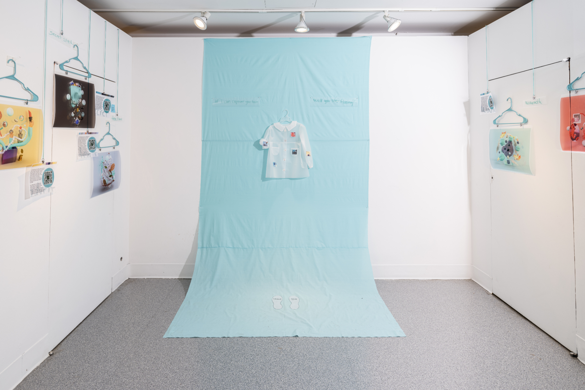 a little dress on a backdrop of fabric in a white cubicle with printed designs hanging on the adjacent walls
