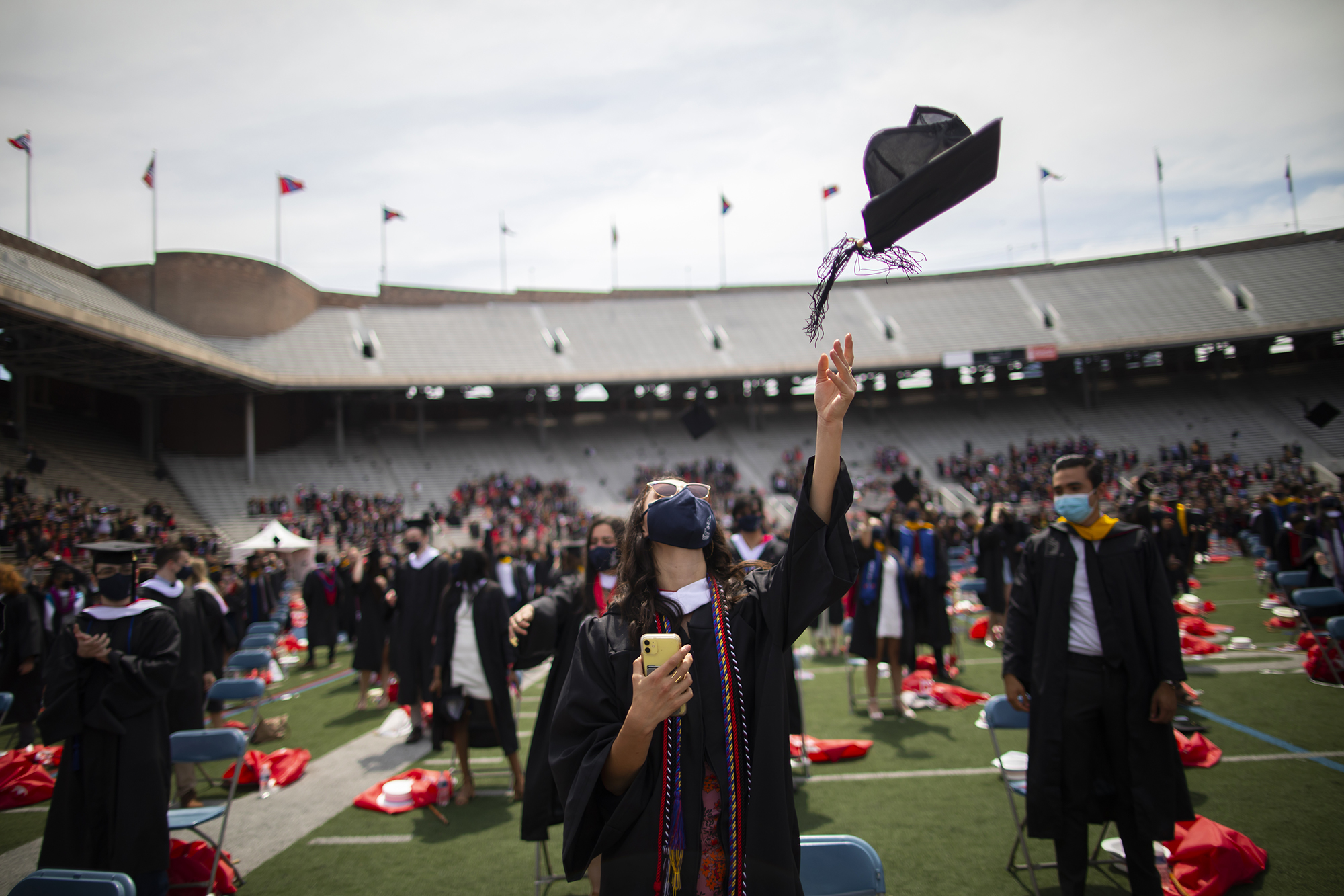 Graduates on Franklin Field throw graduation caps in the air.