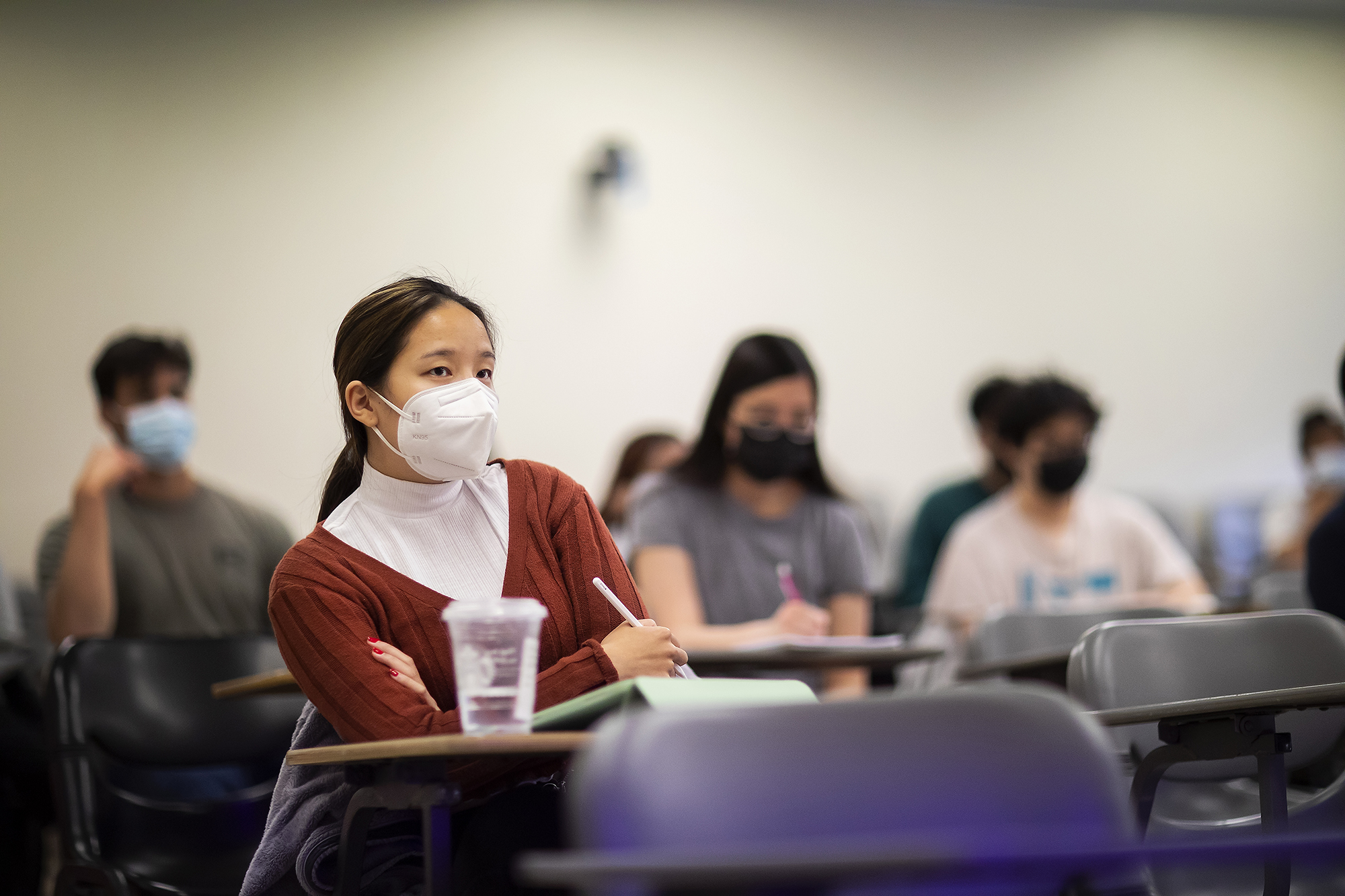 several students sitting in a classroom while wearing masks