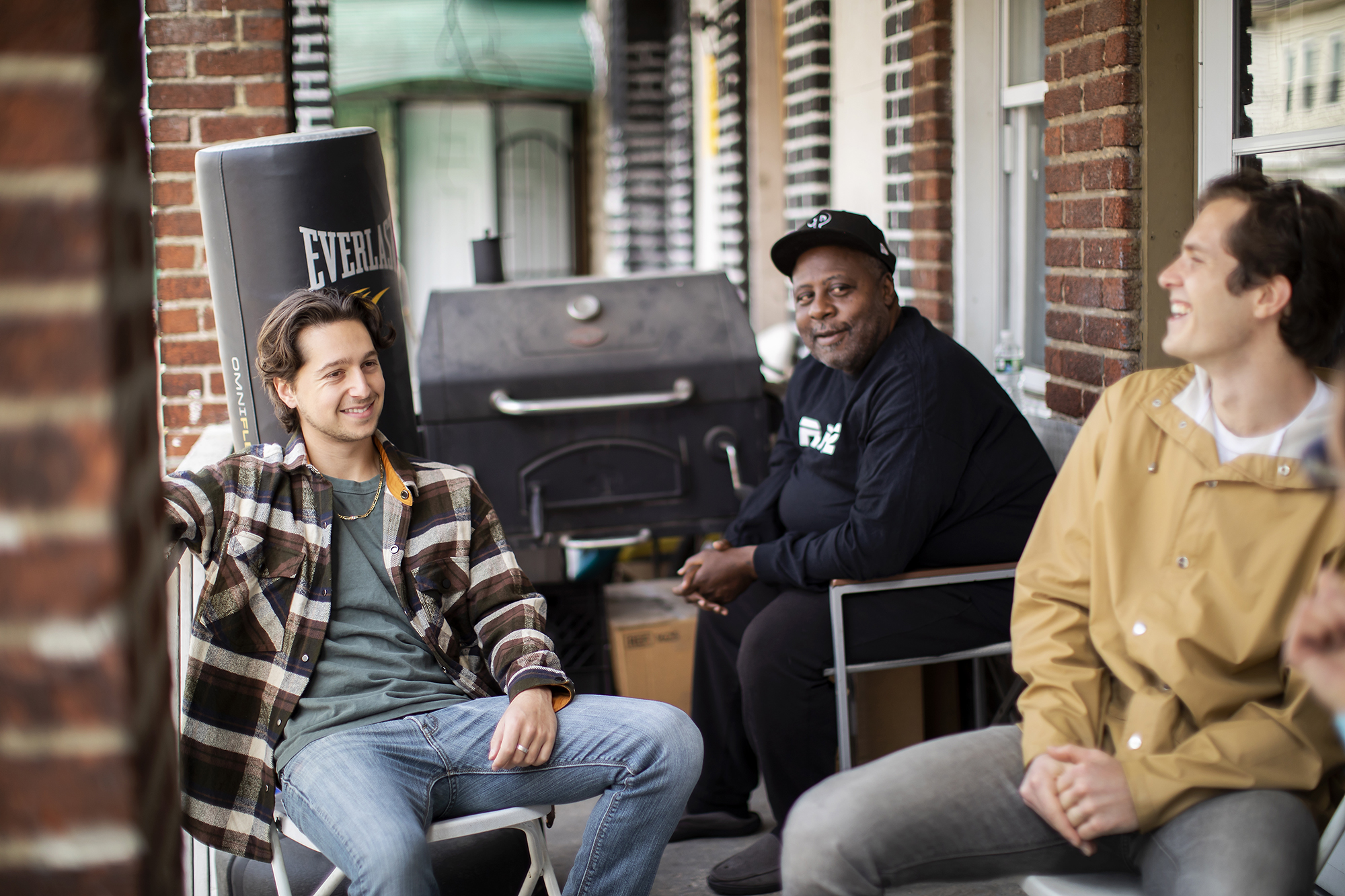 Eli Moraru, Charles Reeves, and Alex Imbot sit on Reeves' front porch in South Philadelphia