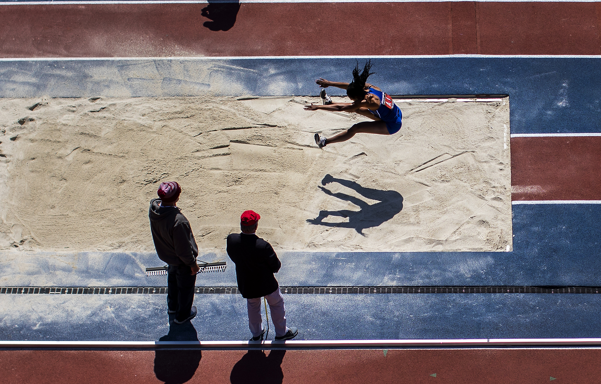 Overhead view of a person in mid-jump competing in a long jump.