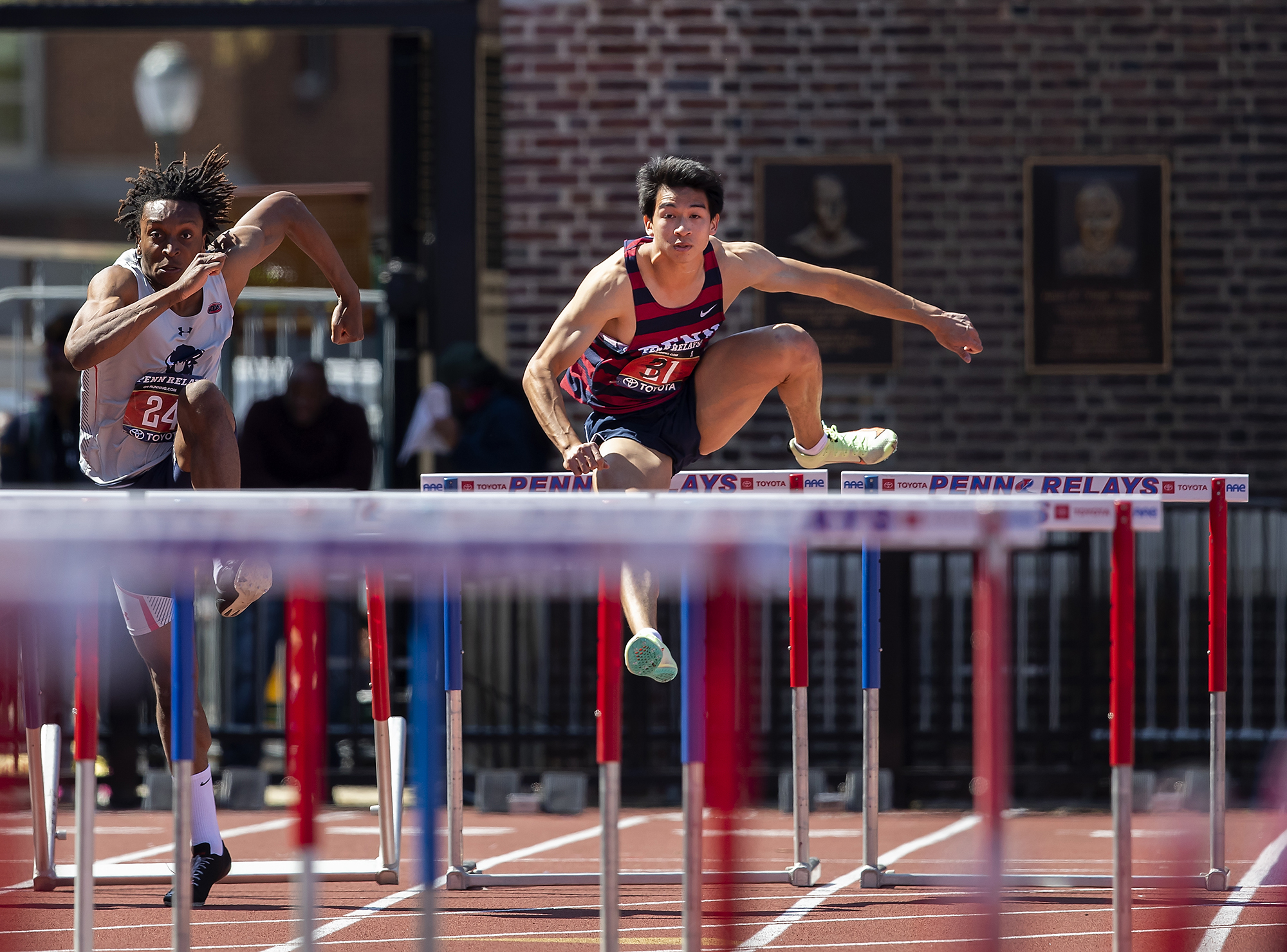 Two racers running and jumping over hurdles.