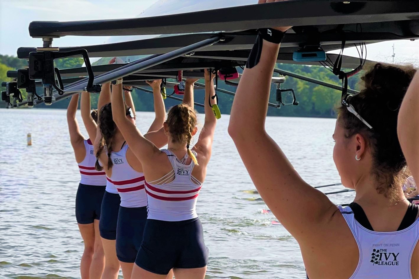 Rowers carry their boat into the water.