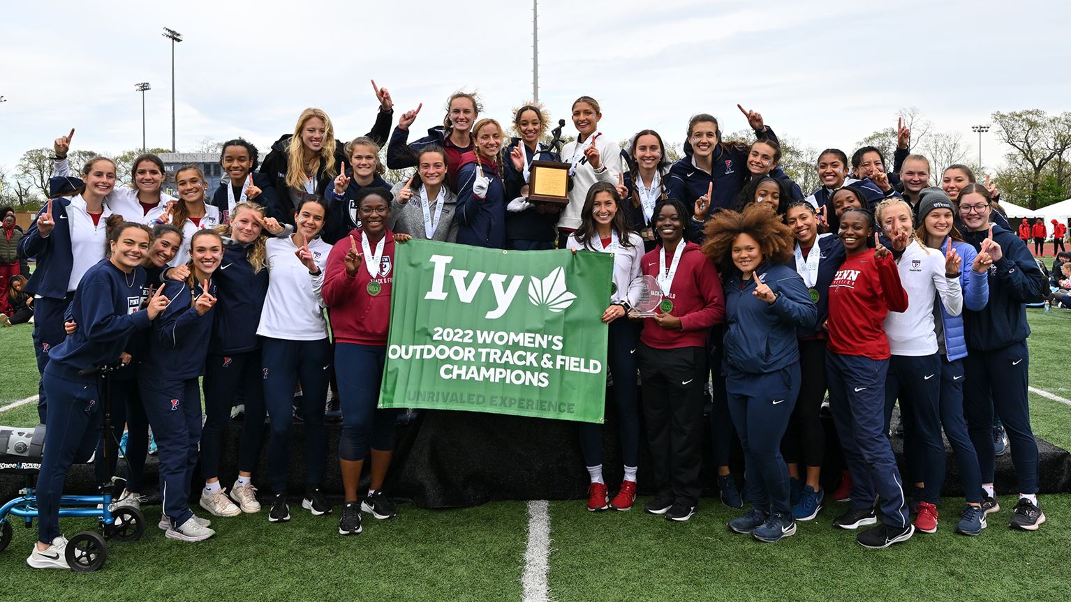 The women's track and field team celebrates with the championship banner.