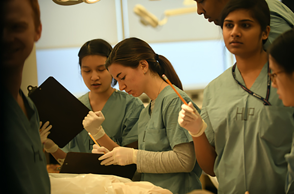 Michaela Hitchner and students in a med school class standing, some with clipboards.