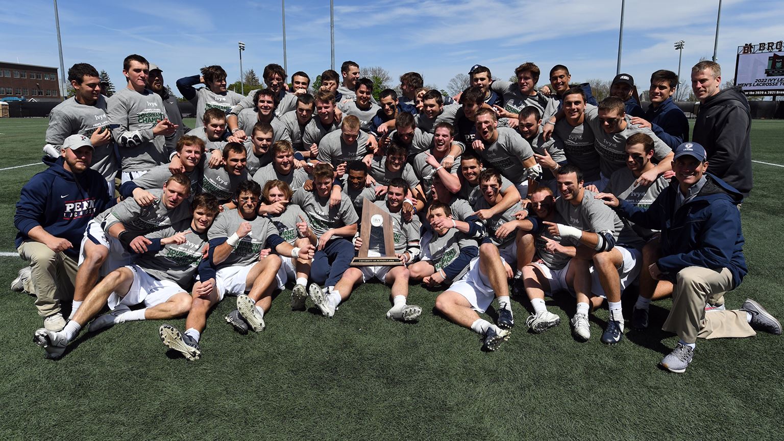 The men's lacrosse team celebrates with the championship trophy.
