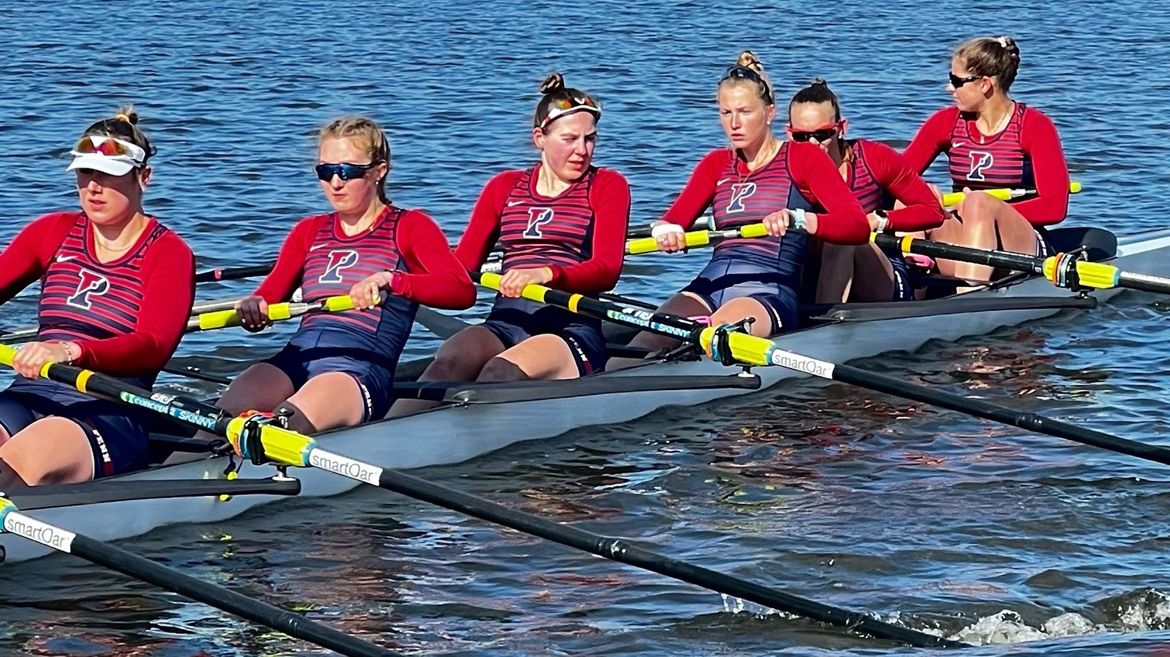 Rowers row in their boat on the water during a competition.