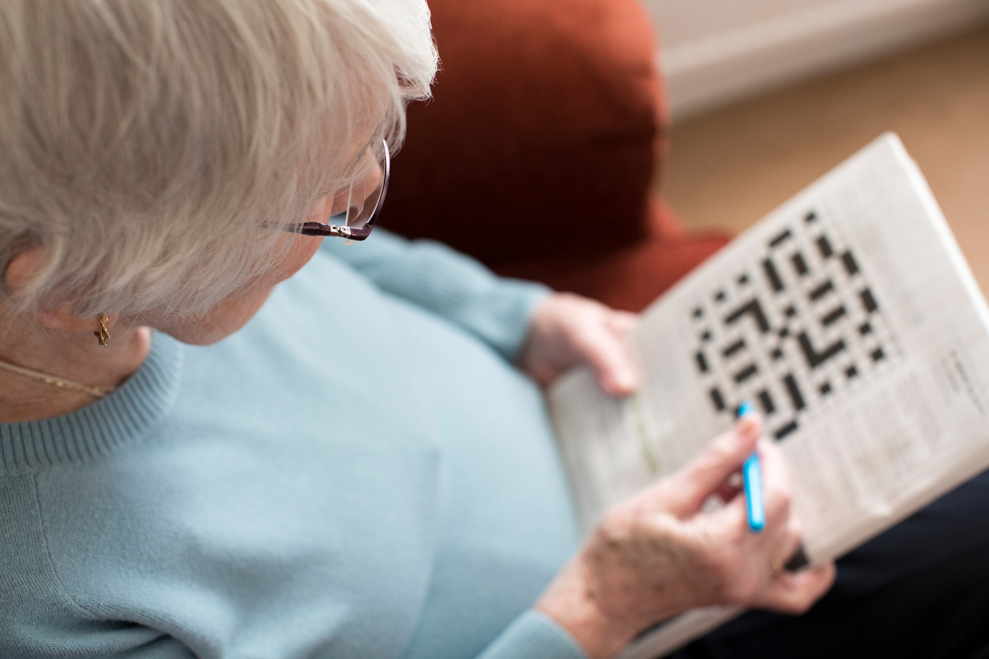 An elderly person doing a crossword puzzle.
