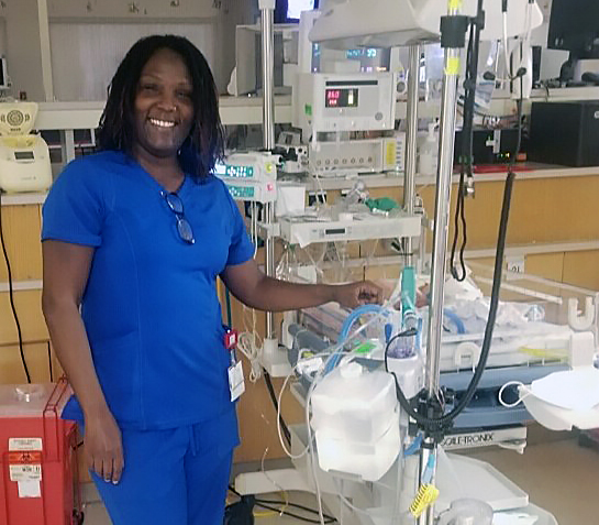 Kimyatta Frazier in scrubs standing in a hospital room.