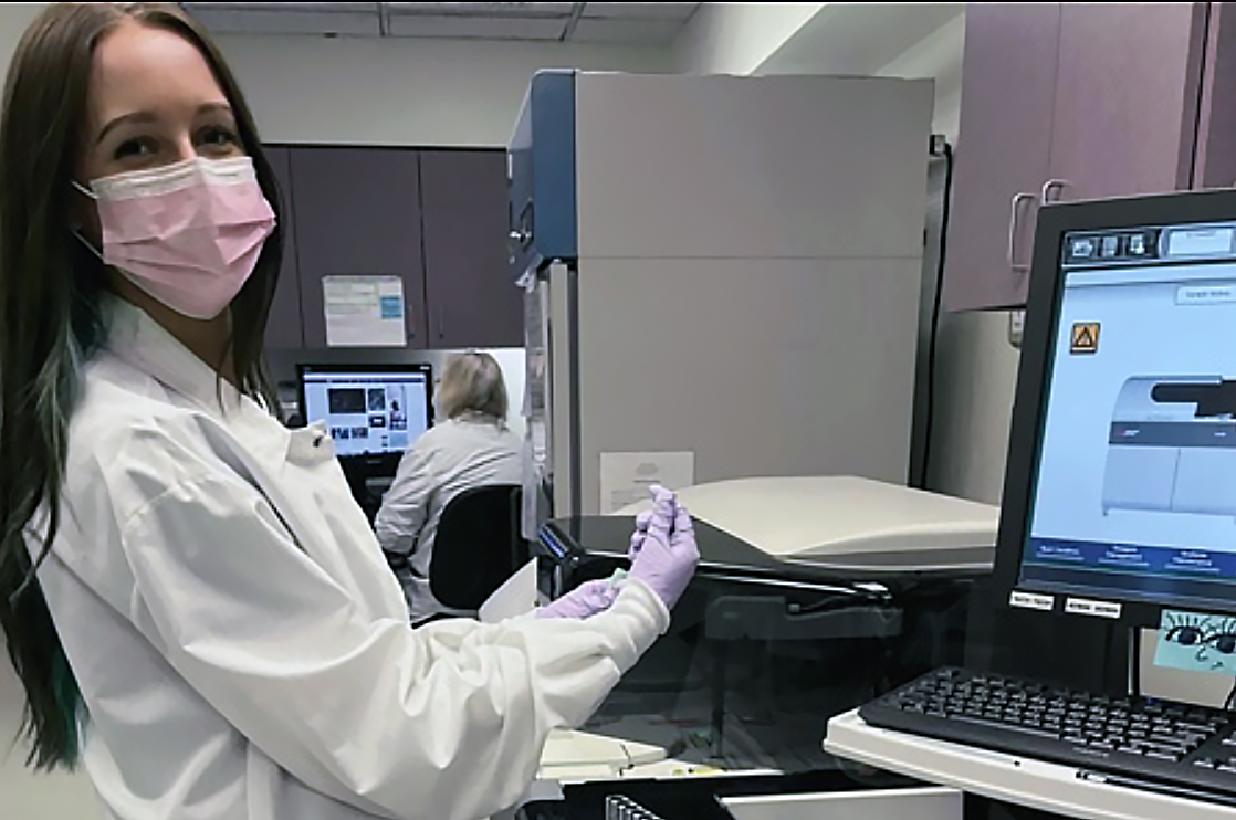 Alison Steinmiller in a face mask at a computer in a lab.