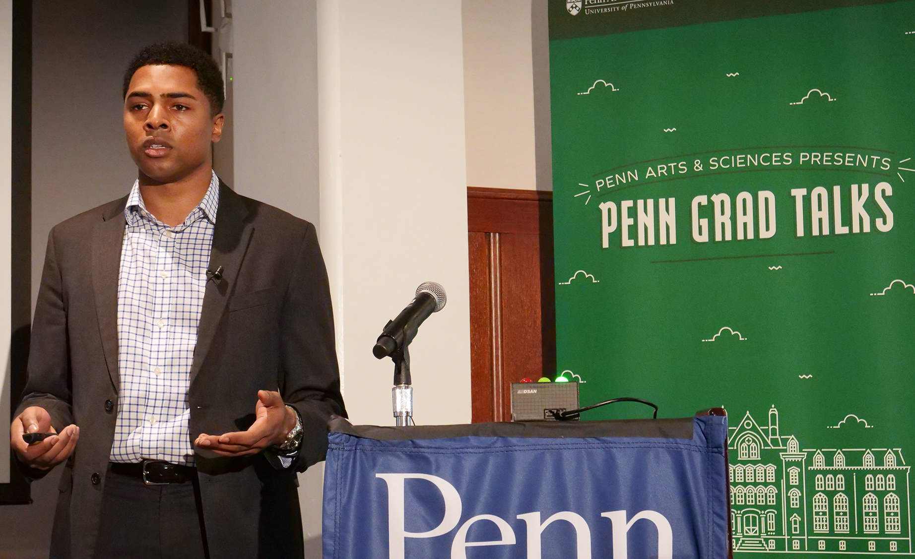 Chad Payne beside podium and microphone with 'Penn Grad Talks' backdrop