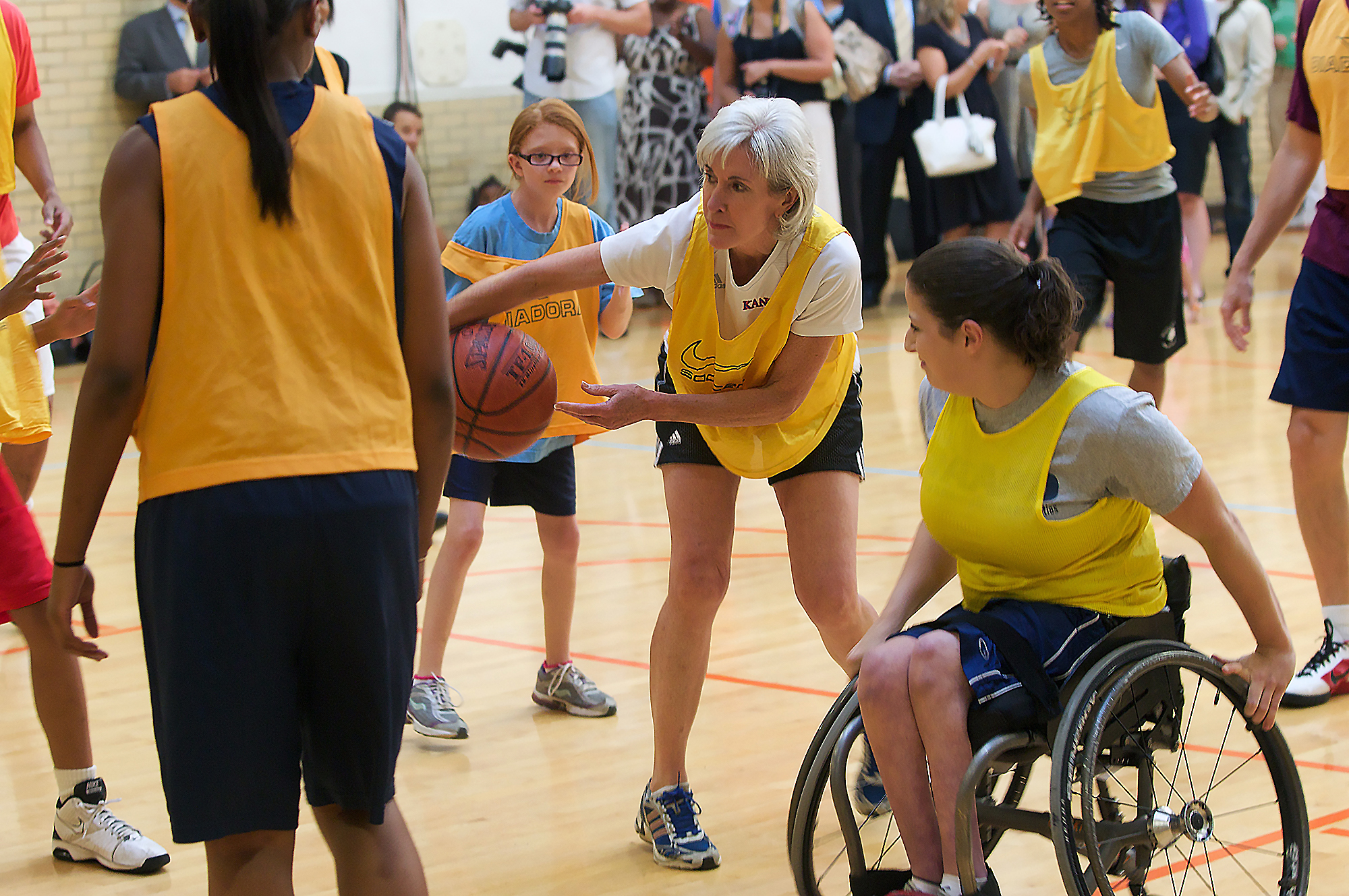 Woman plays basketball with a group of girls, including one in a wheelchair