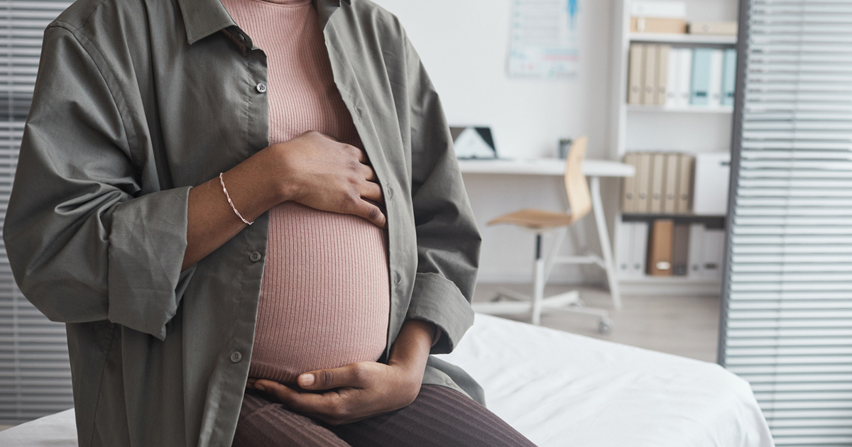 Pregnant person in doctor's office holding belly
