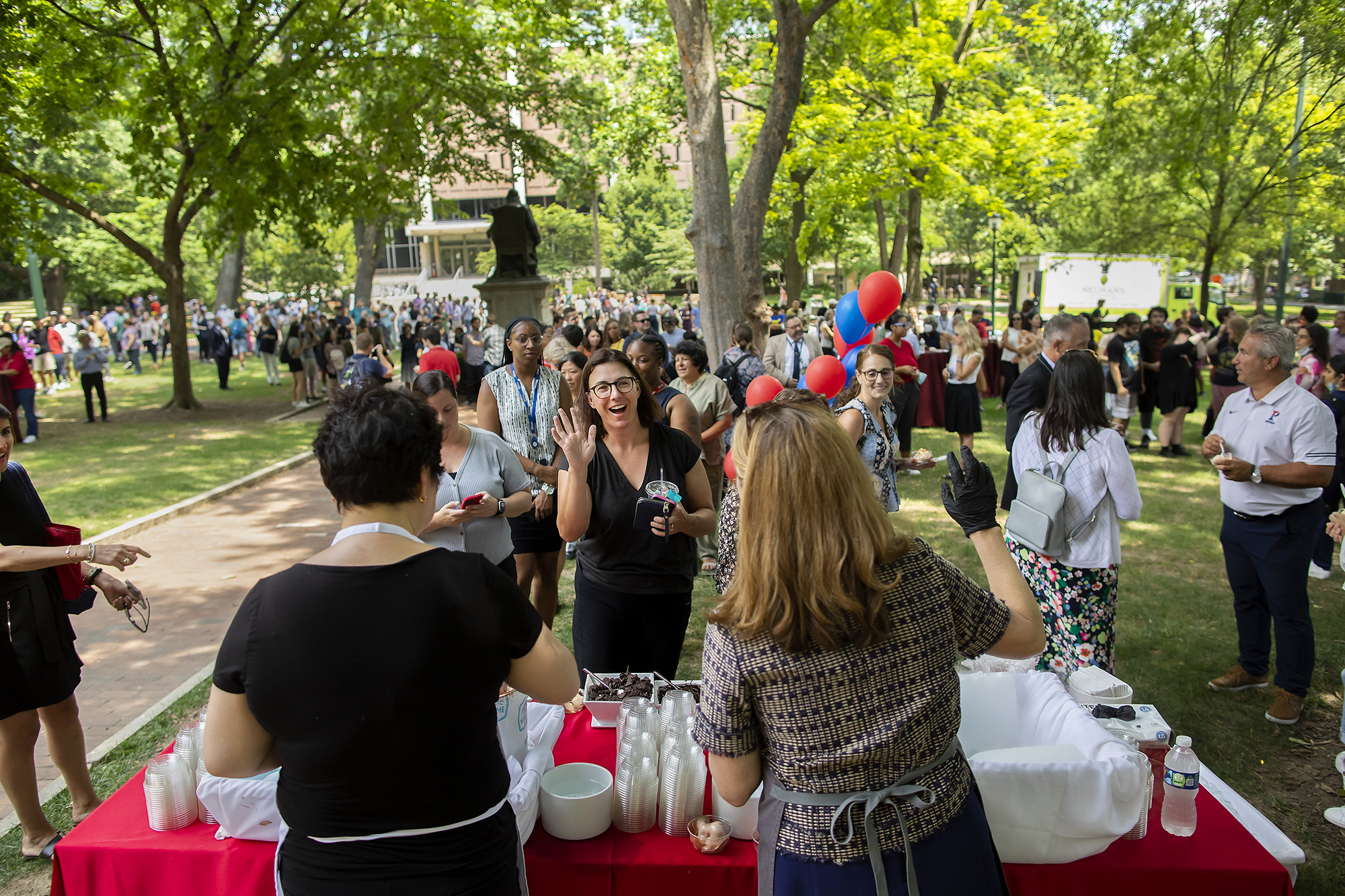 A crowd of people on College Green wait to be served ice cream by Penn President Liz Magill.