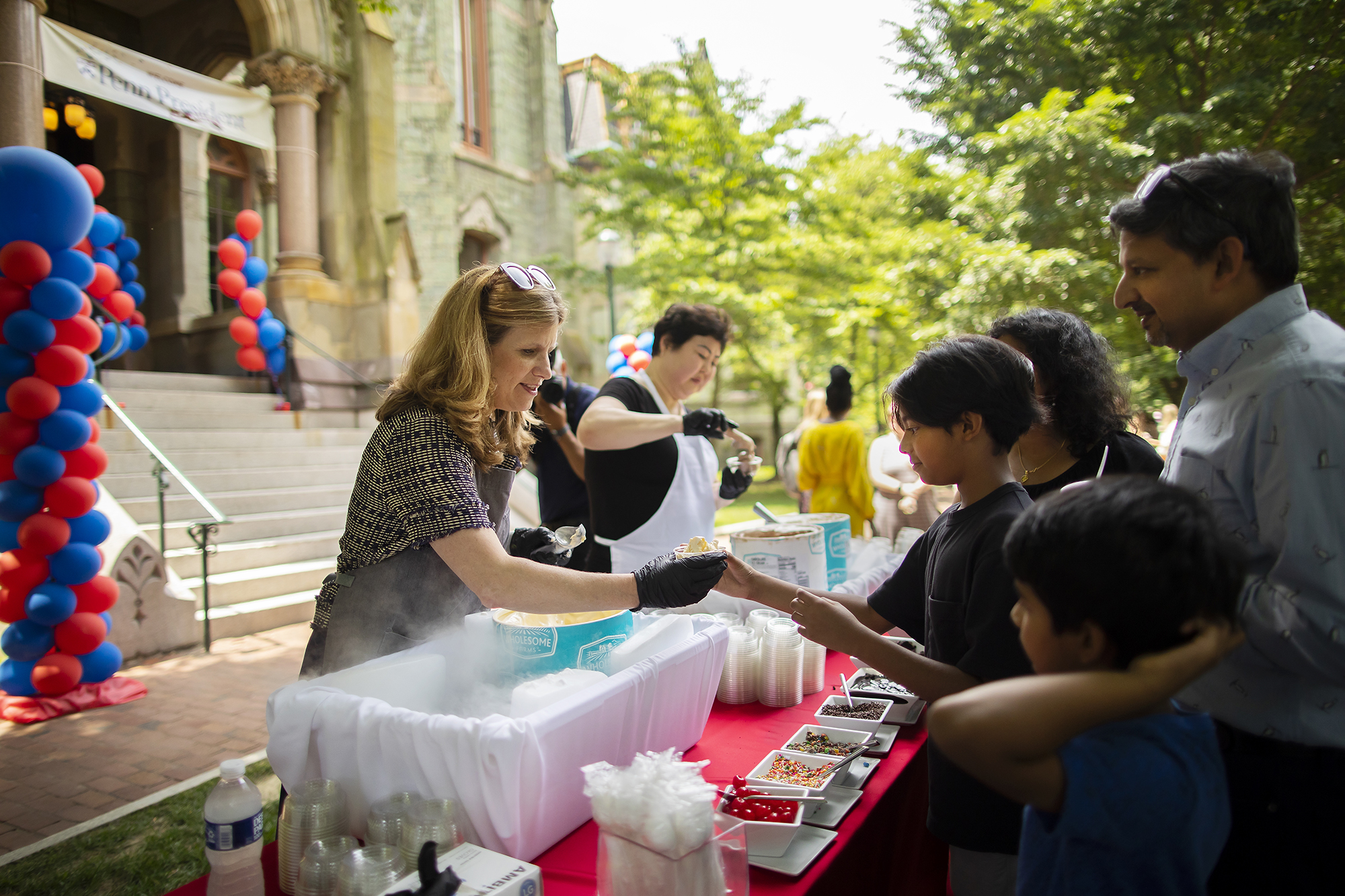 Liz Magill scoops ice cream for a crowd in front of College Hall.