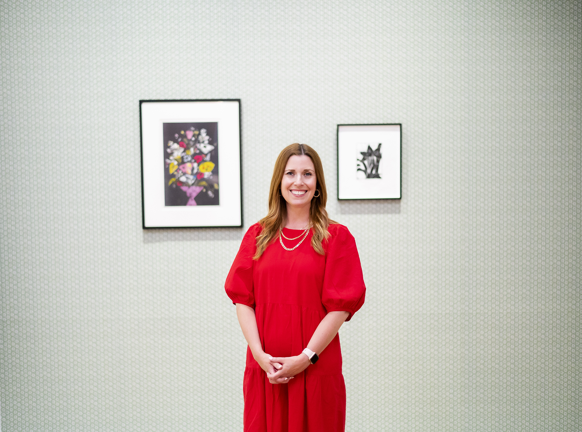Lynn Dolby standing in front of two artworks on a wall 