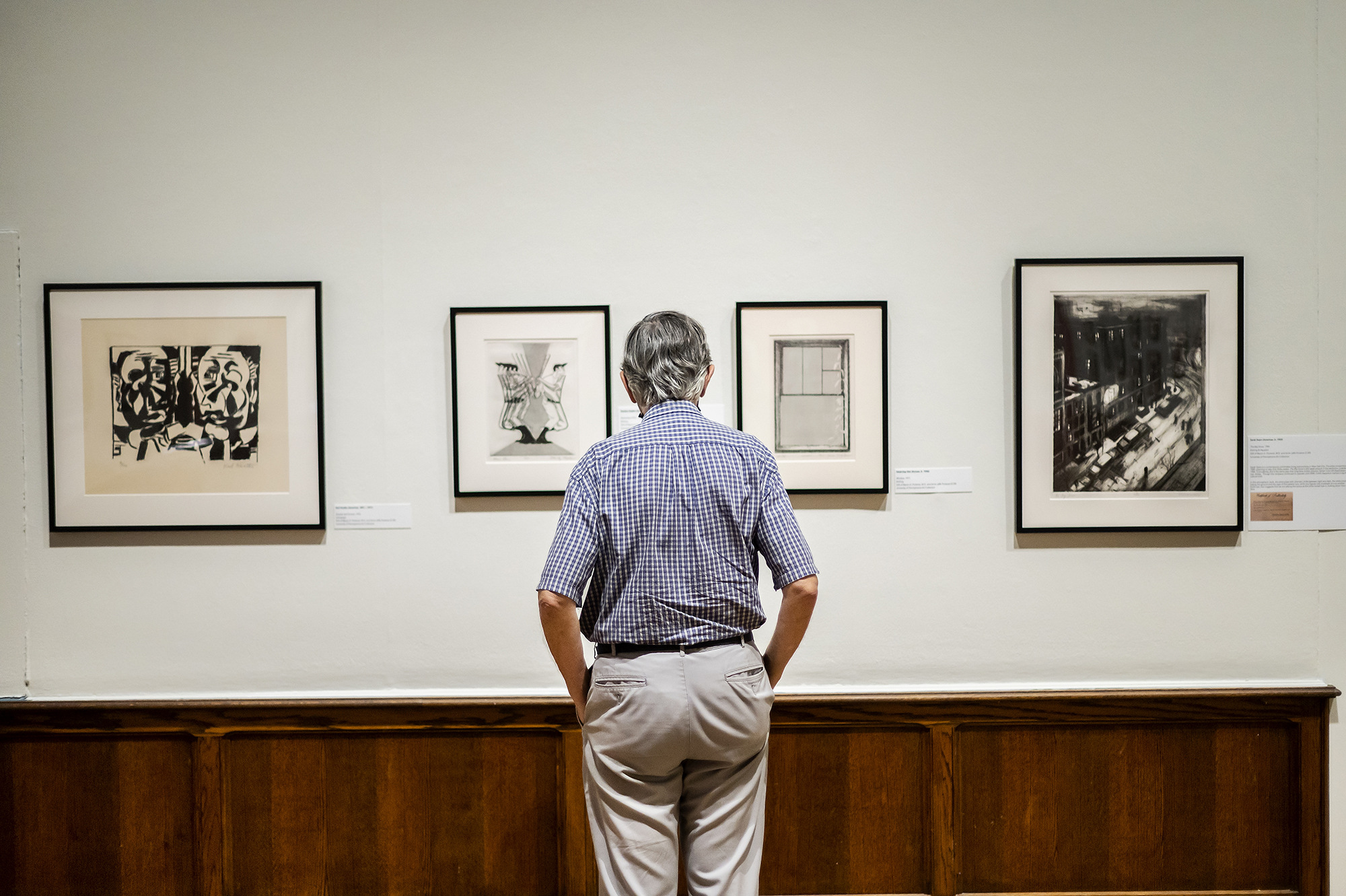 A person looking at artworks hanging on the wall at the Arthur Ross Gallery.
