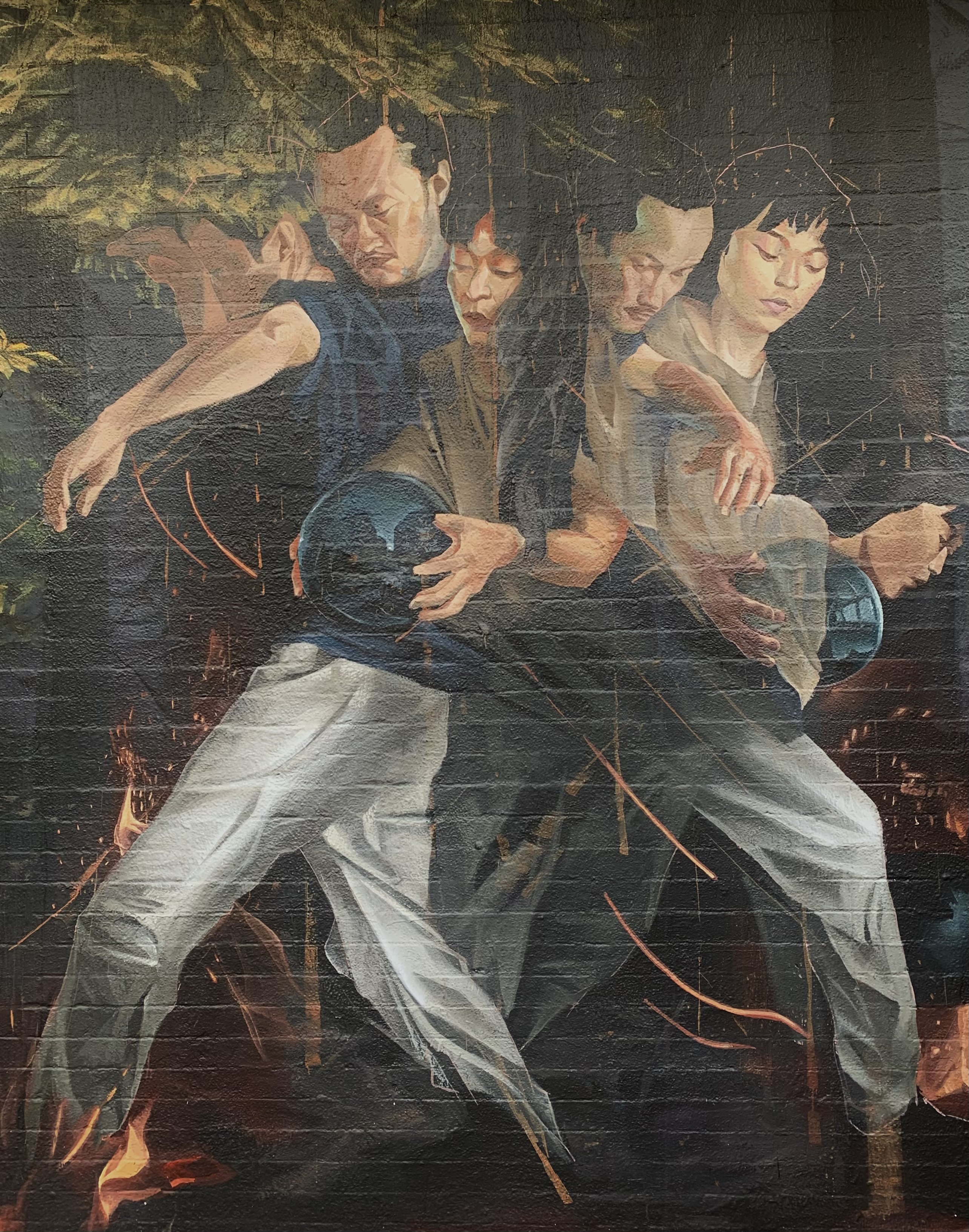 A mural of four figures handling a reflective ball painted on a brink wall