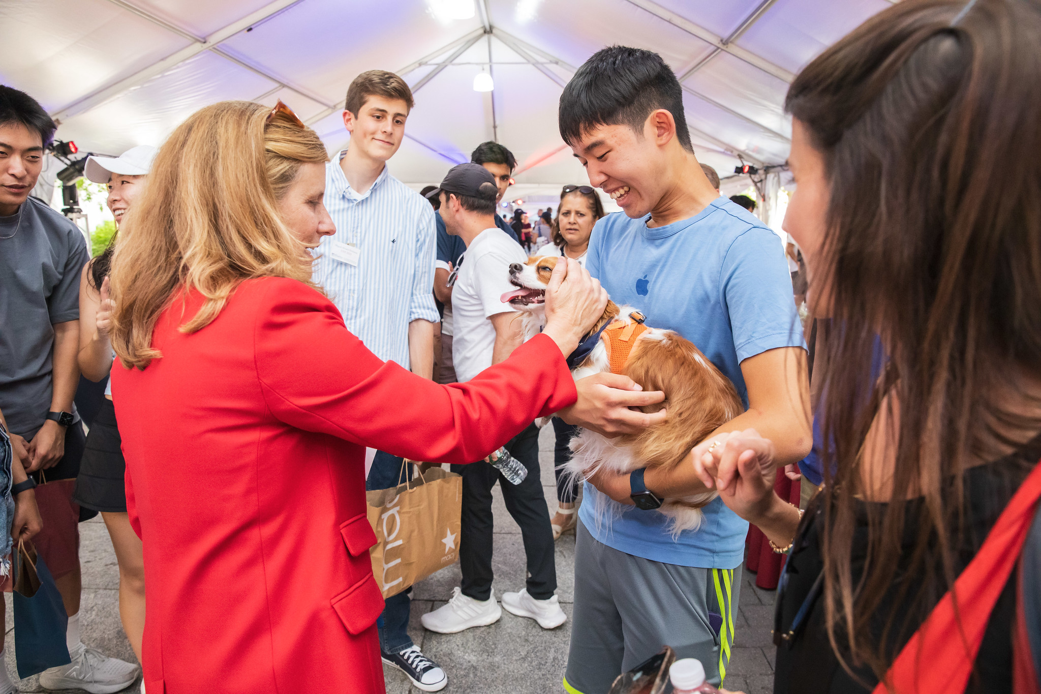 Penn President Liz Magill pets a puppy held by a student.