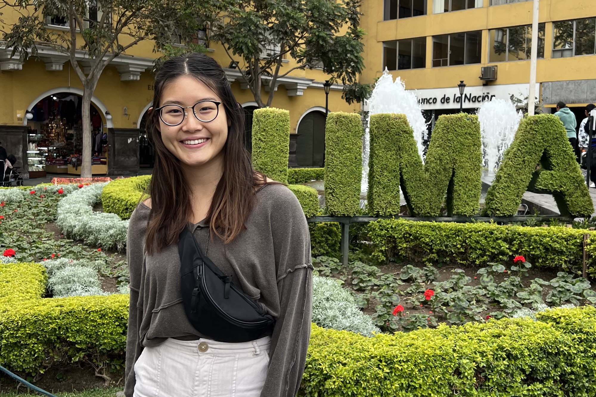 Adrian poses next to garden shrubbery that has been sculpted into the word "LIMA"