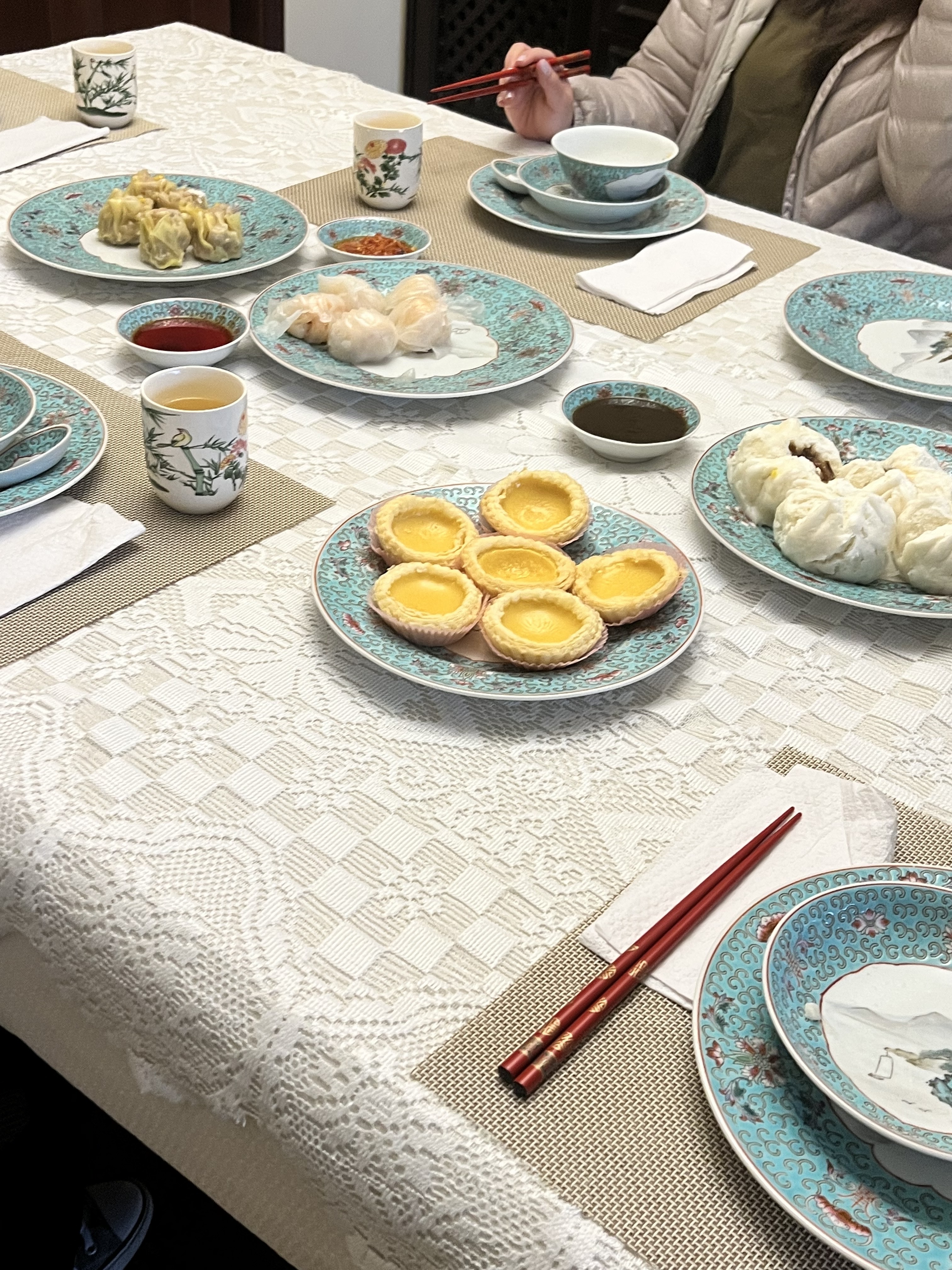 A dim sum table with tea, bao, and dan tat. 