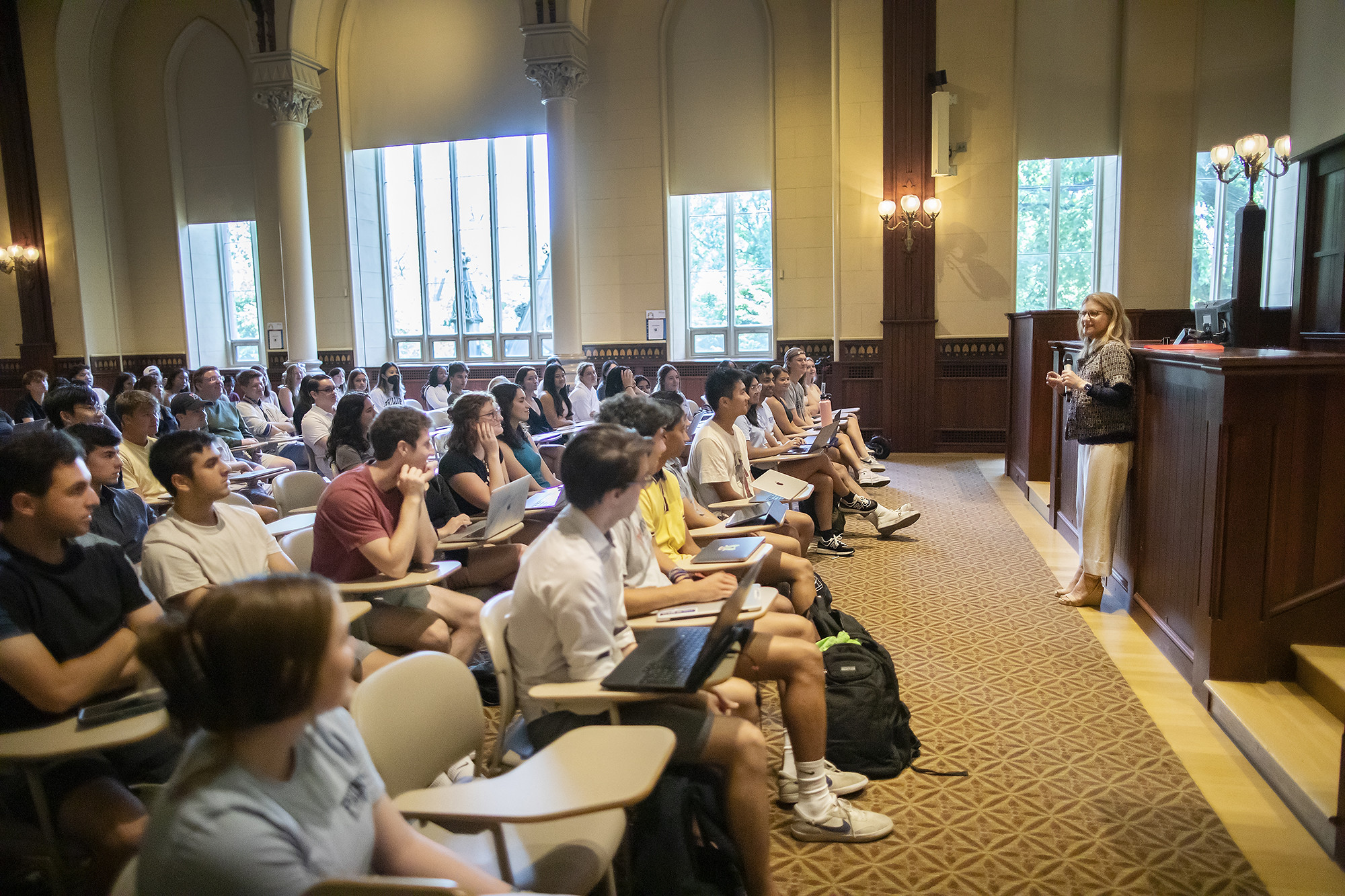 Penn President Liz Magill addresses a large room of people seated at desks.