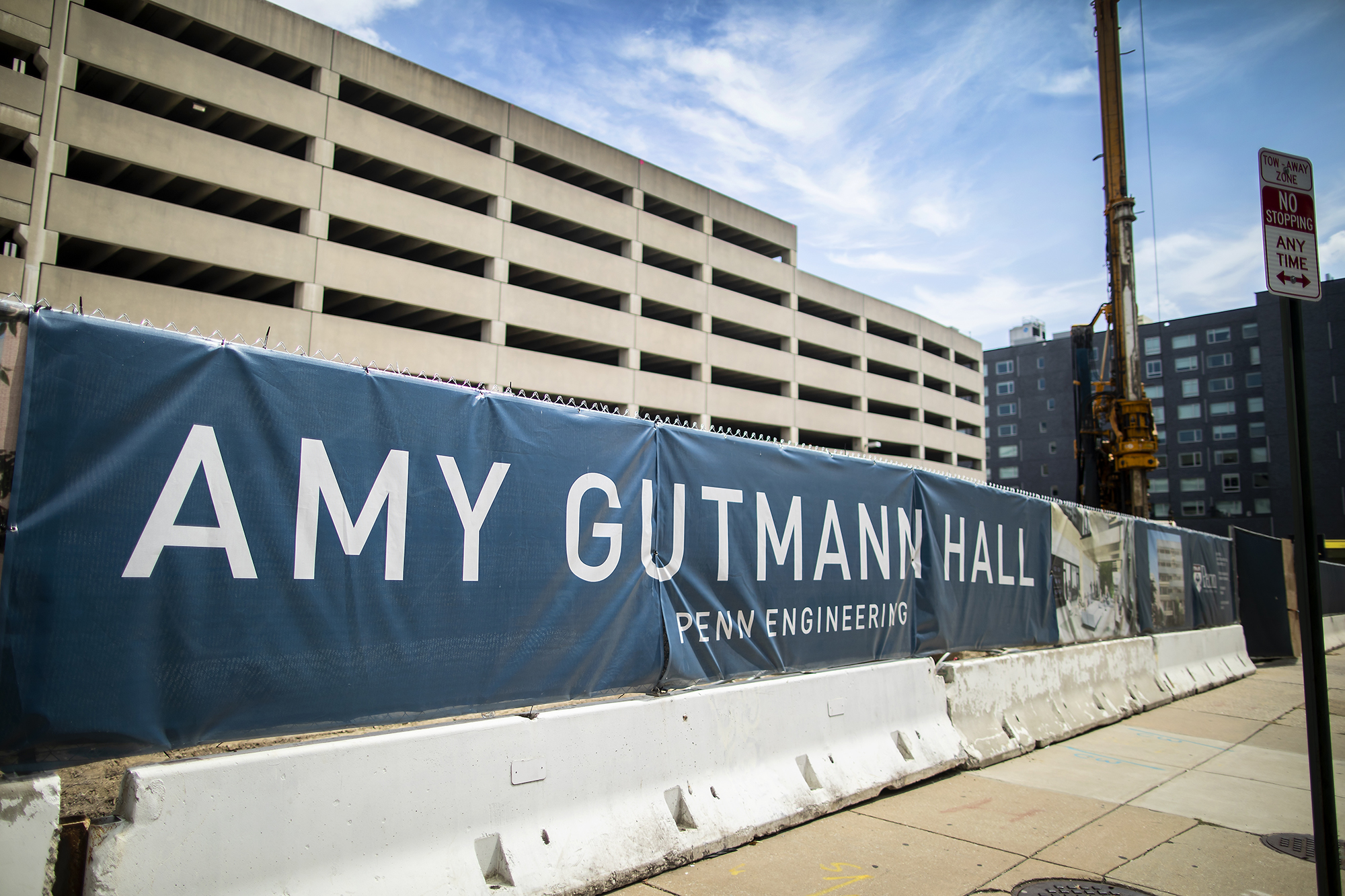 Construction site with a banner on a sidewalk barrier that reads AMY GUTMANN HALL.