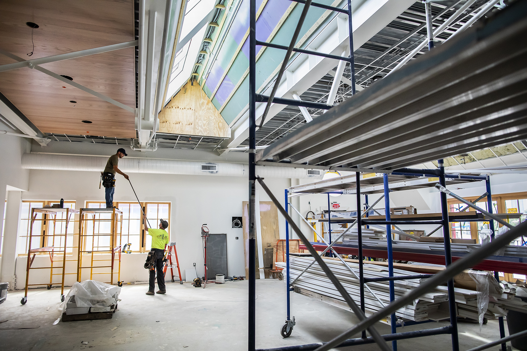 Two construction workers work on the interior of Penn Boathouse.
