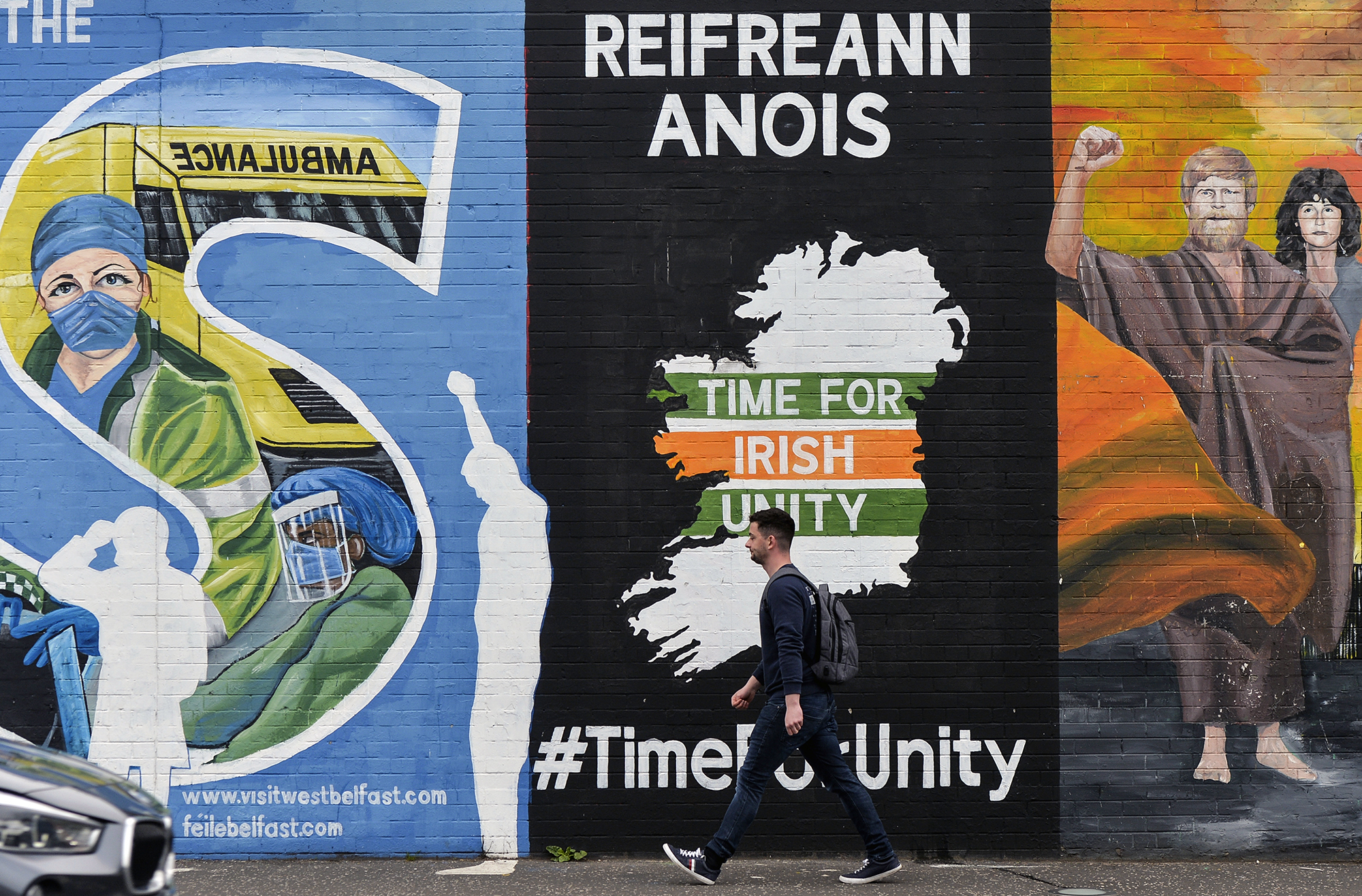 A man walks past graffiti about Irish unification on a wall in Belfast. 