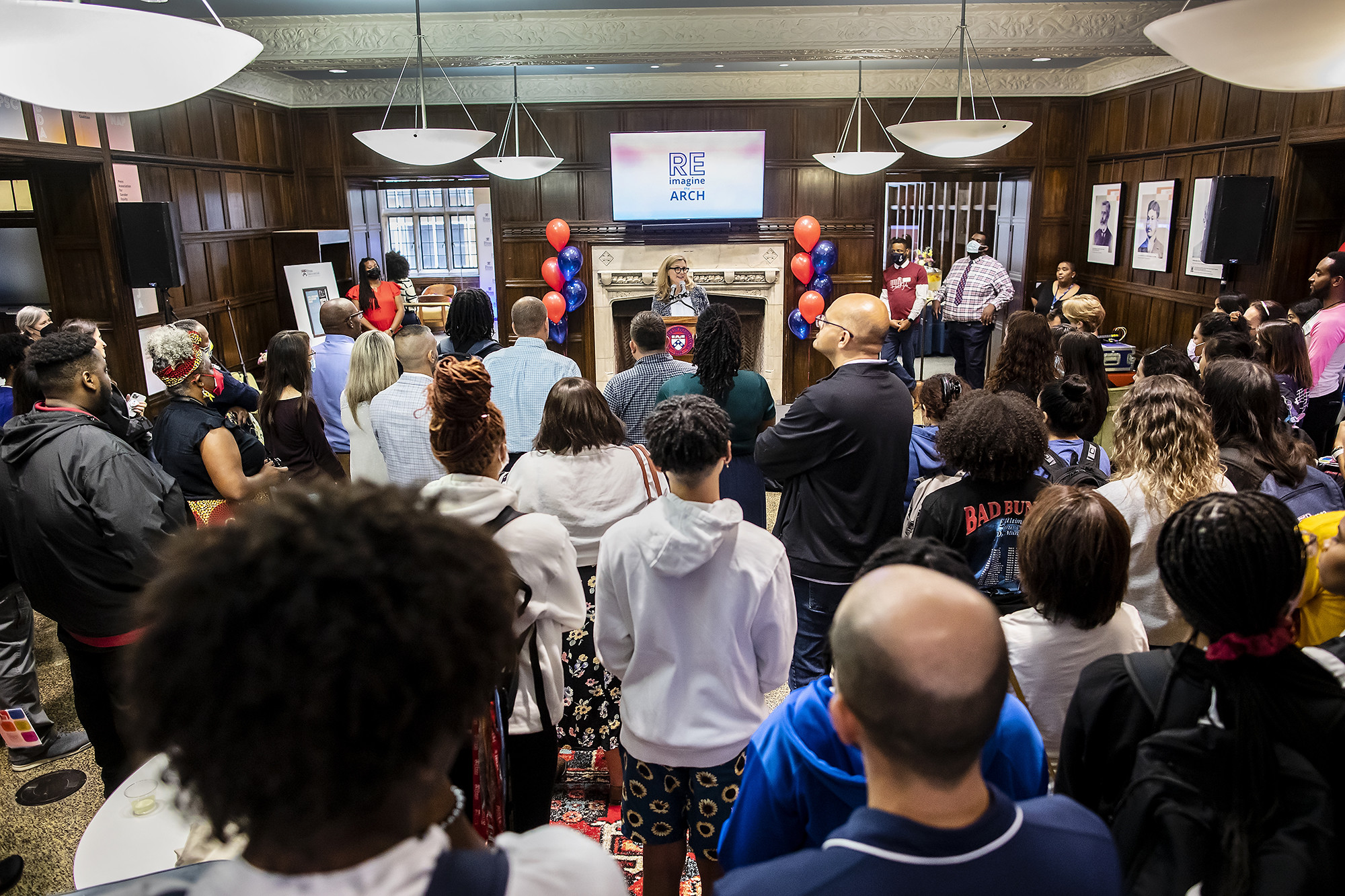 Guests in a large lobby watch President Magill give a speech from a podium. 