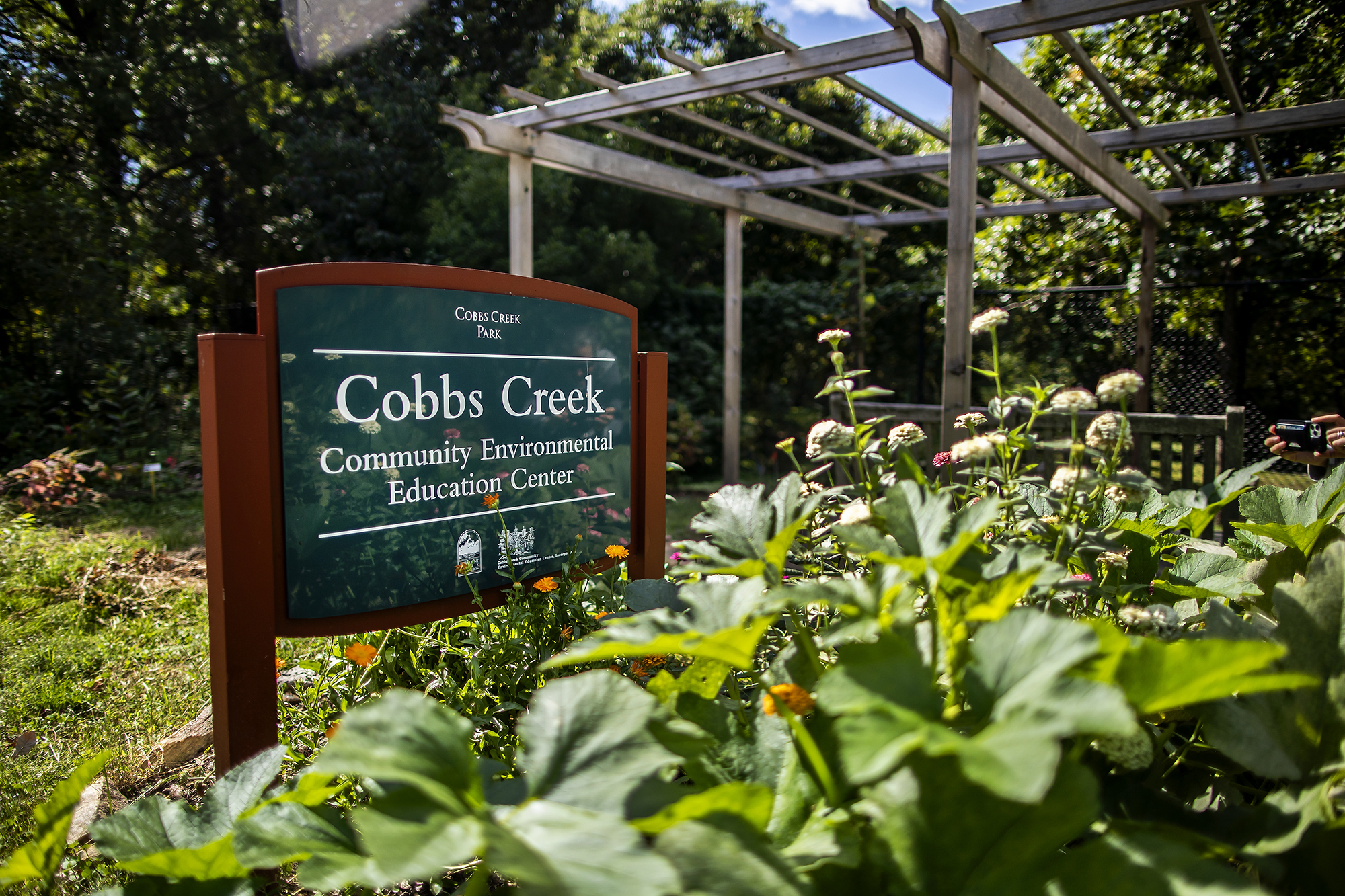 Sign in front of a garden that reads Cobbs Creek Community Environmental Education Center.