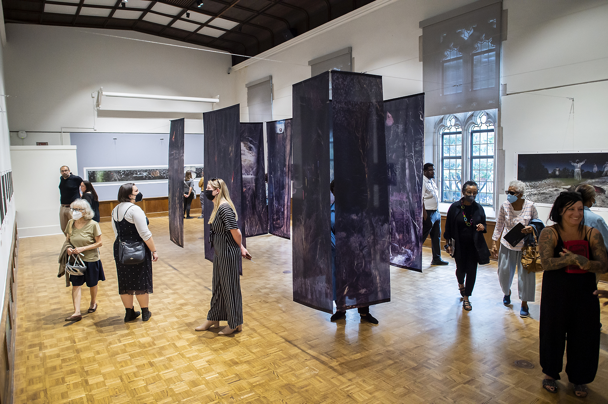 a dozen people walk around the Arthur Ross Gallery exhibition 