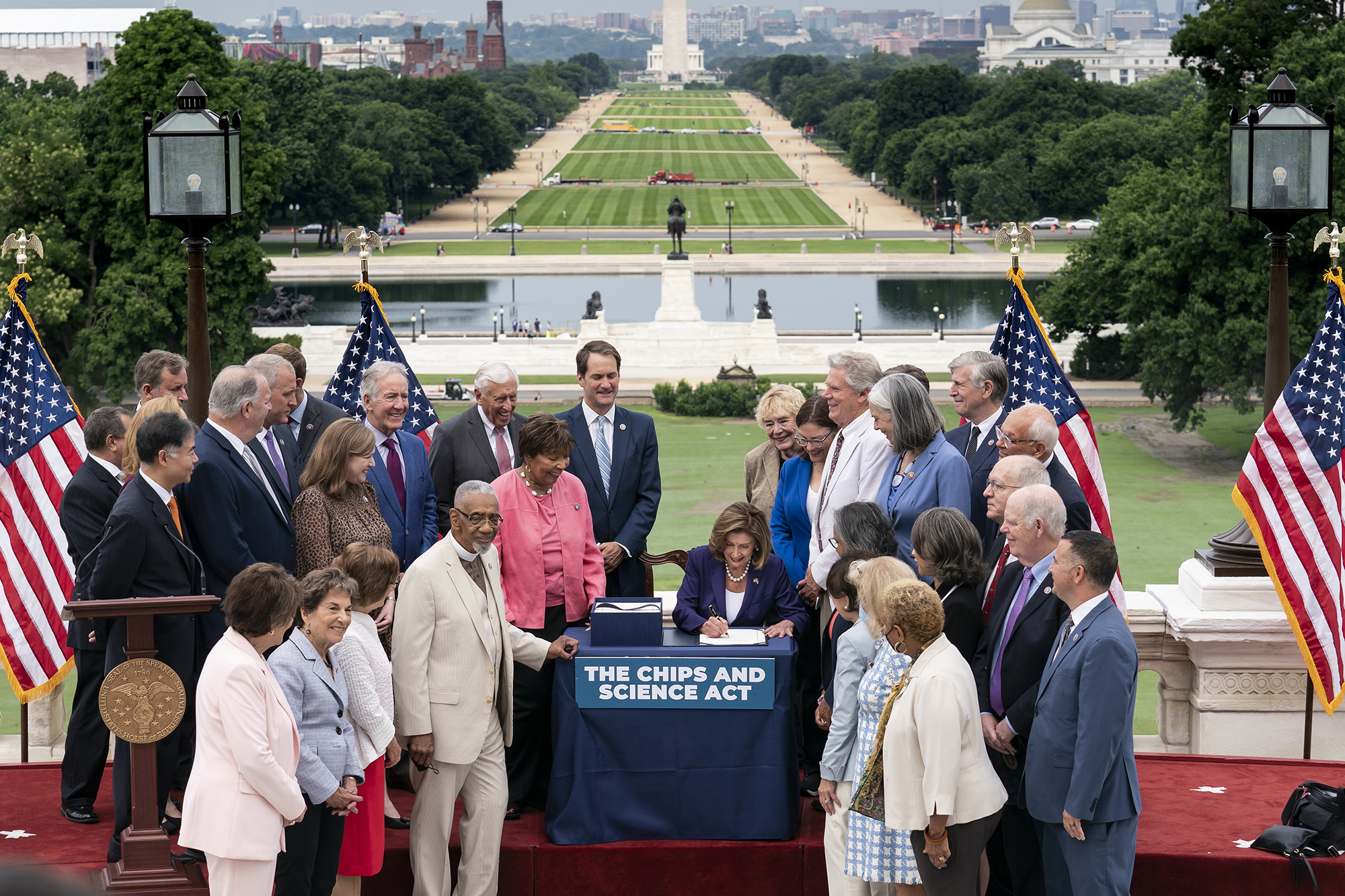 Group of people at a signing huddled around a table labeled 'The CHIPS and Science Act'