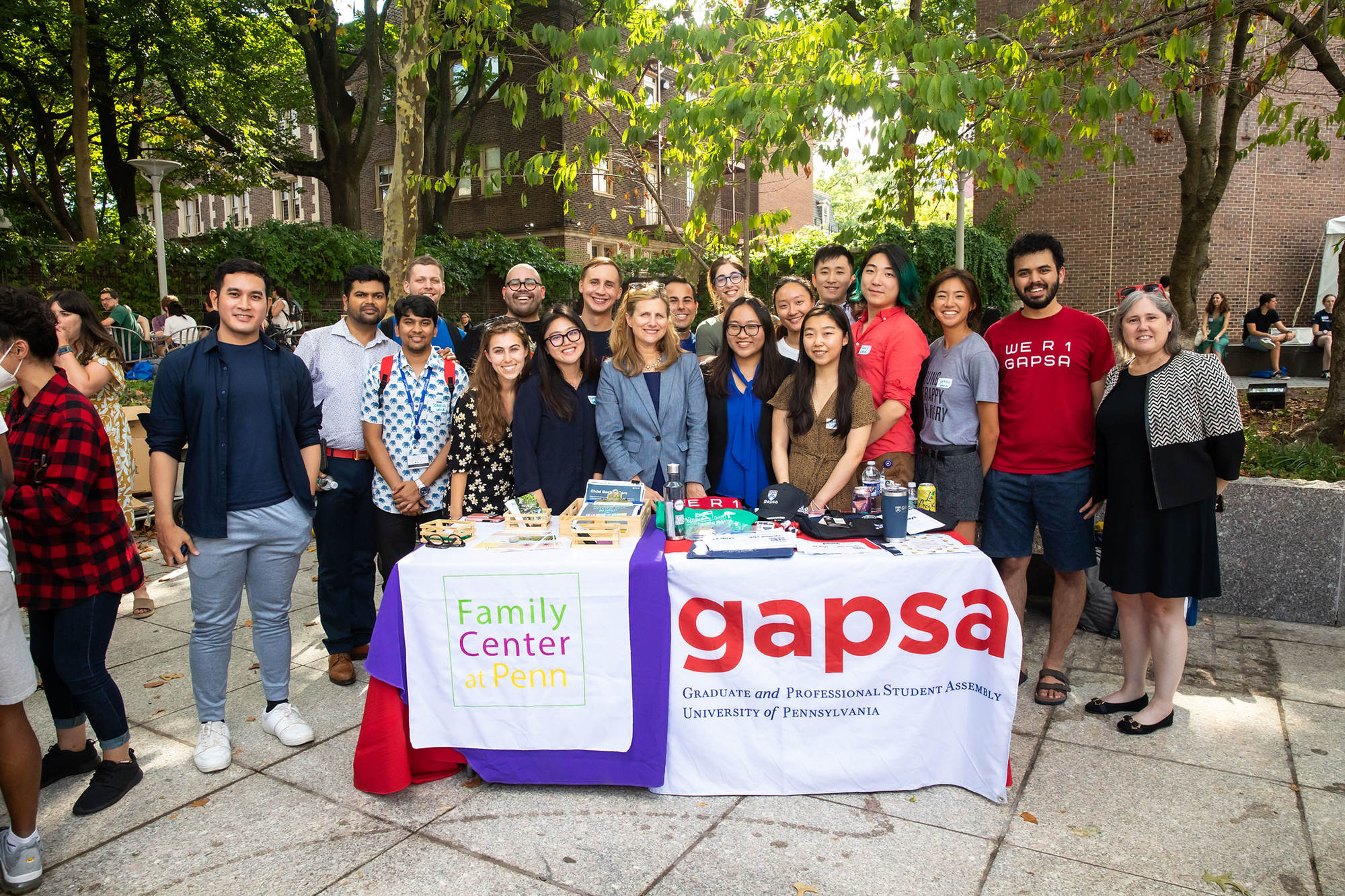 Penn President Liz Magill stands with a large group of graduate and professional students at the GAPSA and Penn Family Center at Penn tables on Penn’s campus.