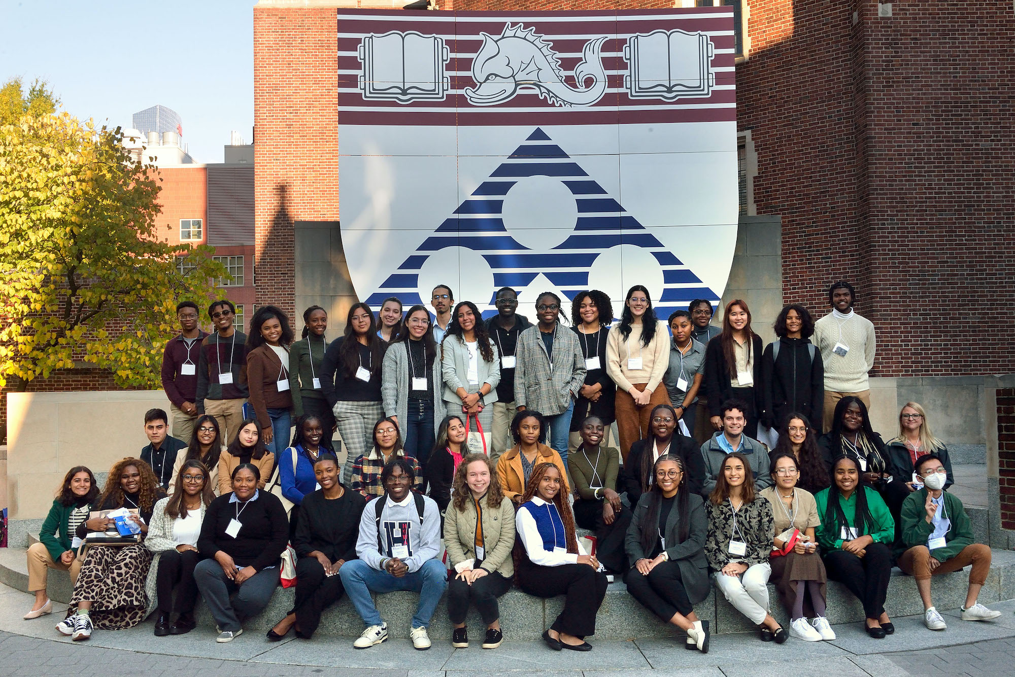 Large group of students posing in front of Penn logo on campus