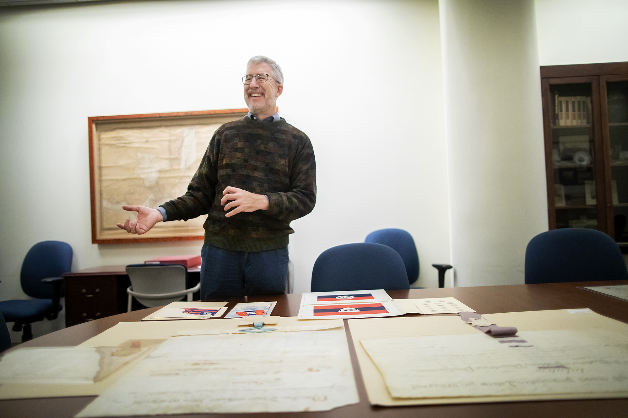 Archives curator stands over a table with ephemera from historical Penn inaugurations.