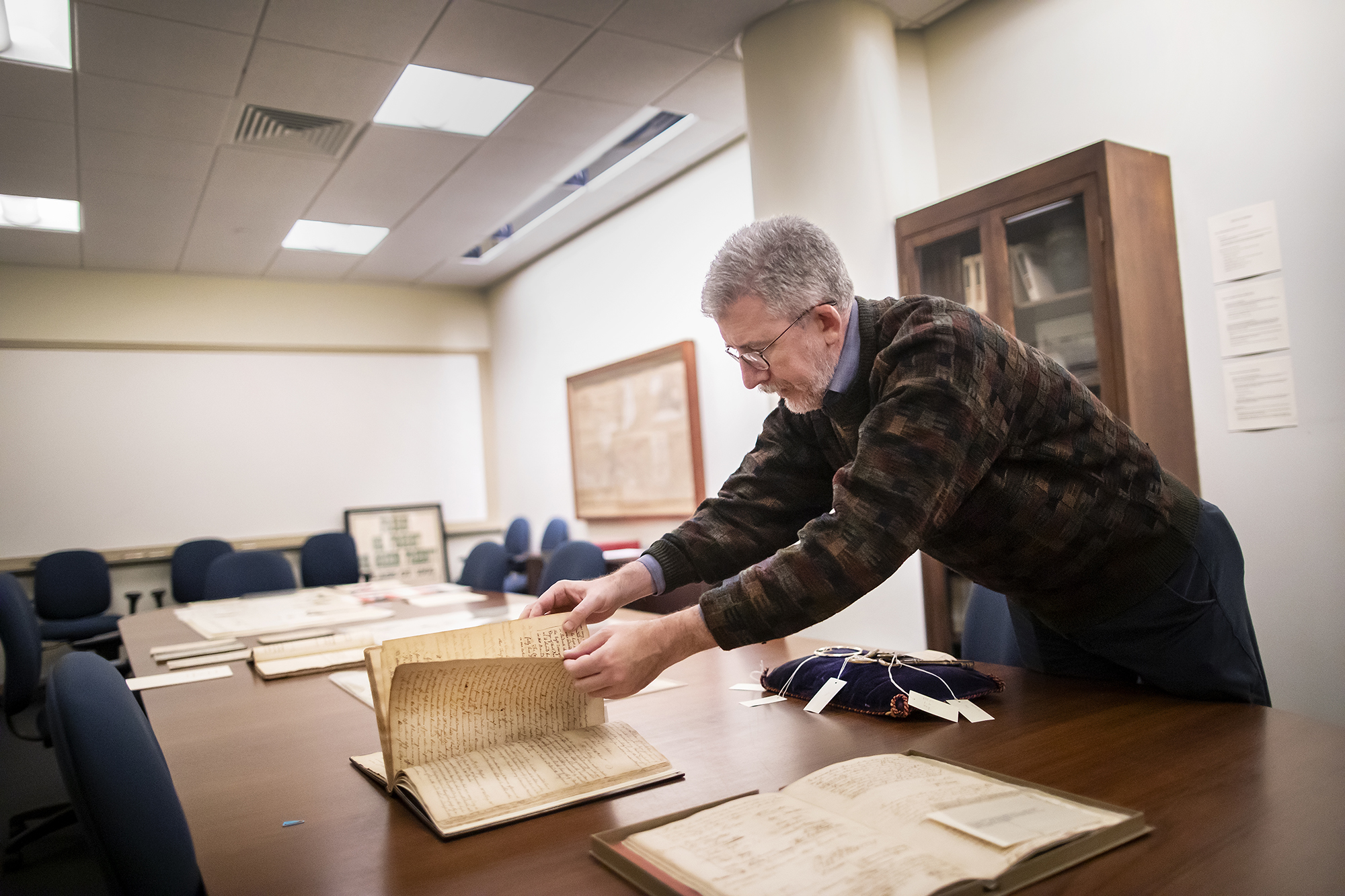 Archives curator flipping through pages of a historic book from the Penn Archives.