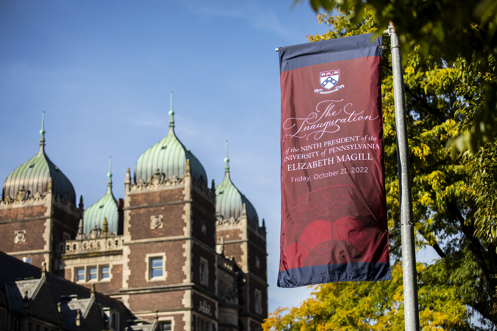 An inauguration banner hanging from a pole on Penn’s campus with the Quad in the background.