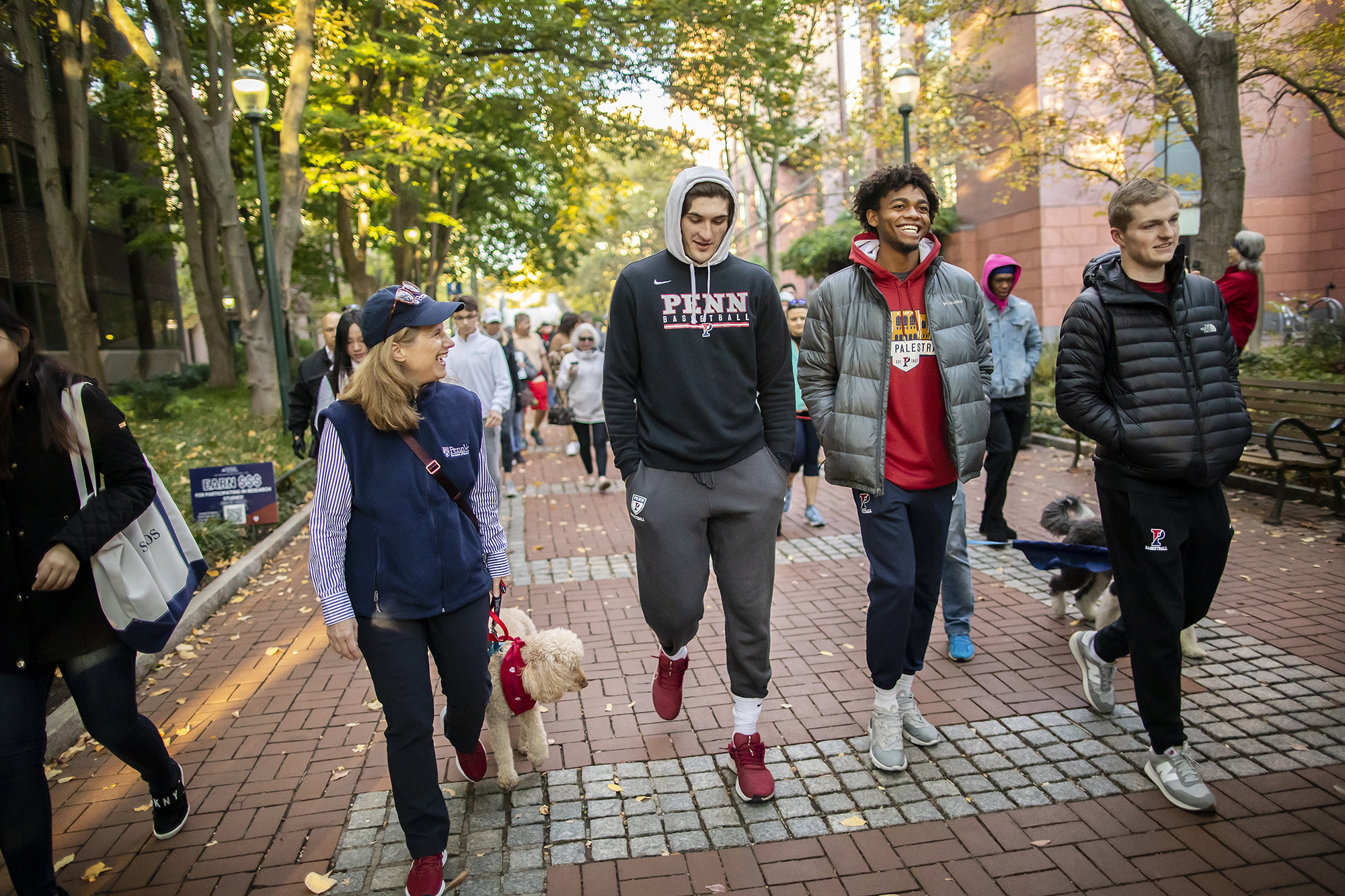 penn president magill walks with basketball players