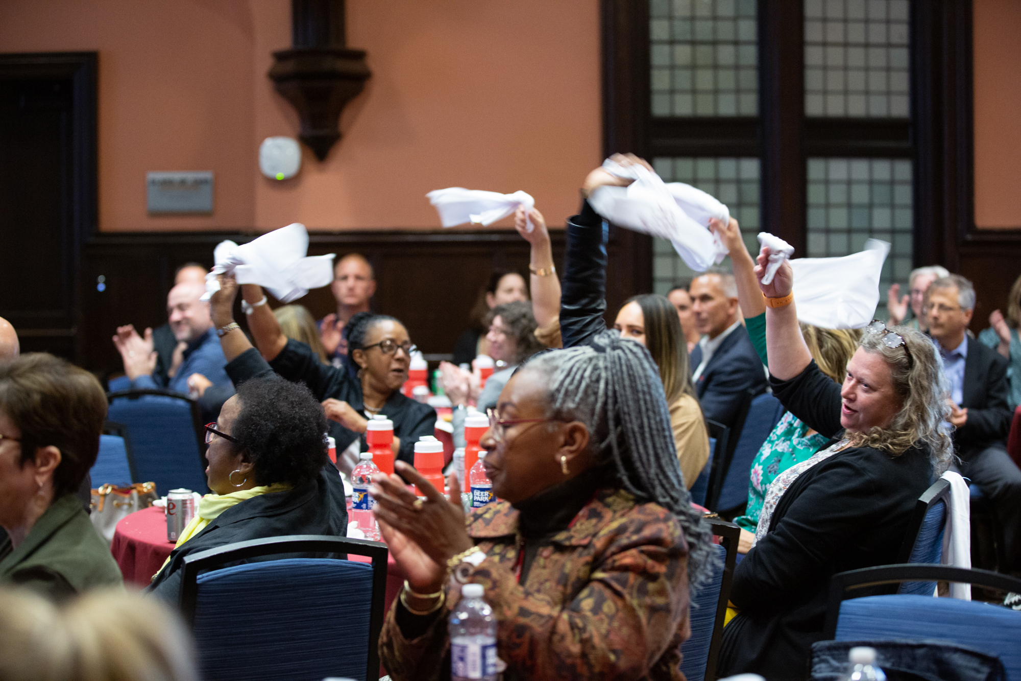 People waving towels in the air while seated at tables.